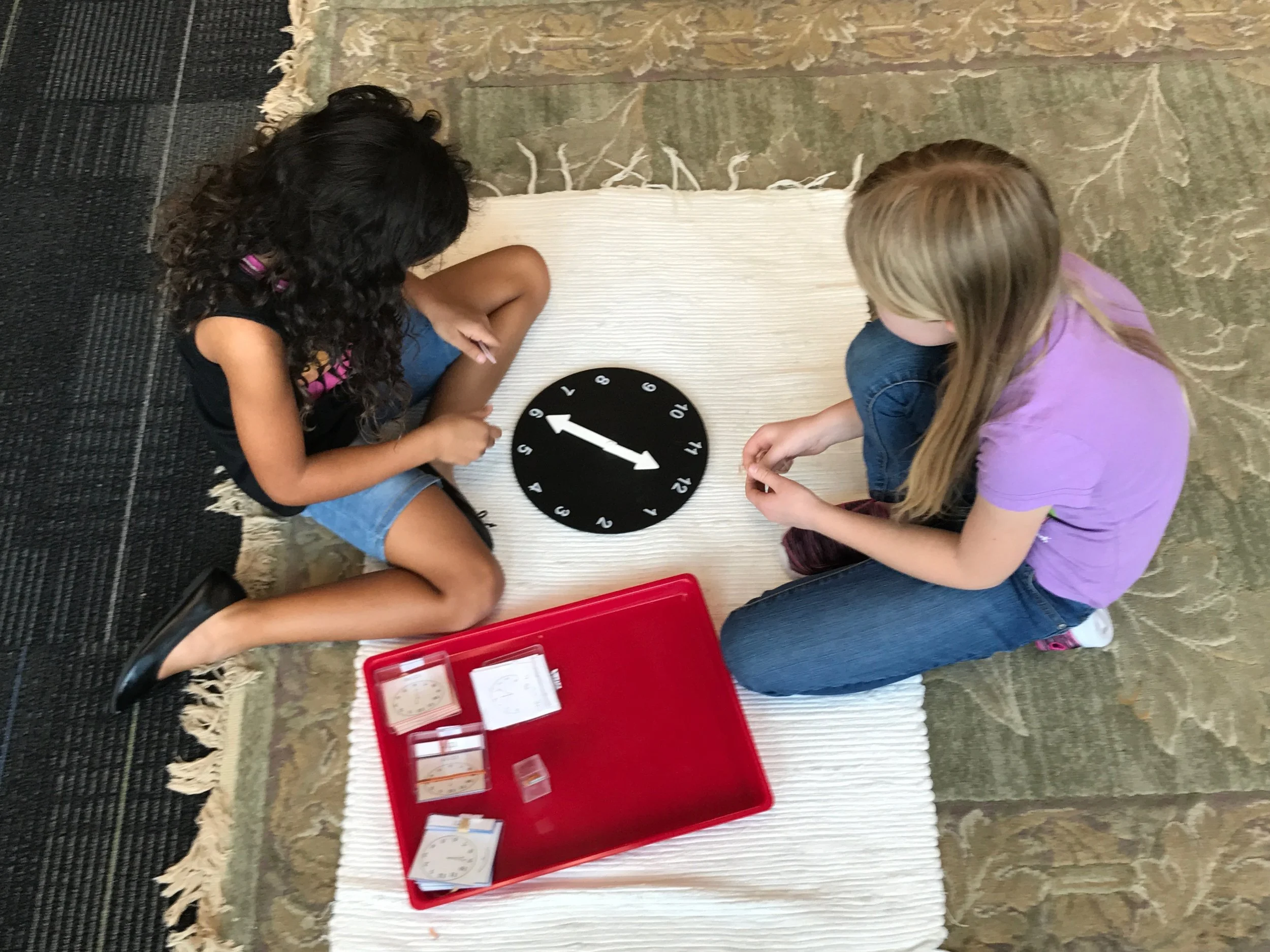  A third grade student gives a second grade student a lesson on telling time. &nbsp;The children love to give lessons to each other, and it helps them to solidify the knowledge in their own heads. &nbsp; 