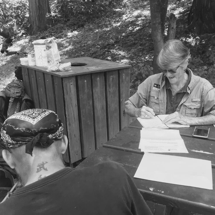 Sierra Roots advocate Alice Litton assists a homeless participant at the weekly Sierra Roots community lunch at Pioneer Park.
