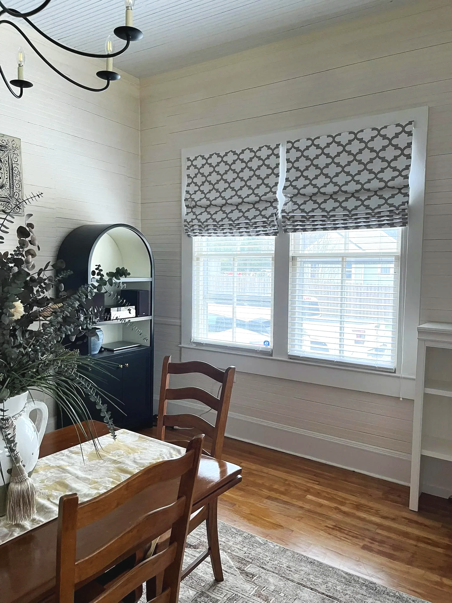 A traditional dining room with grey and white roman shades