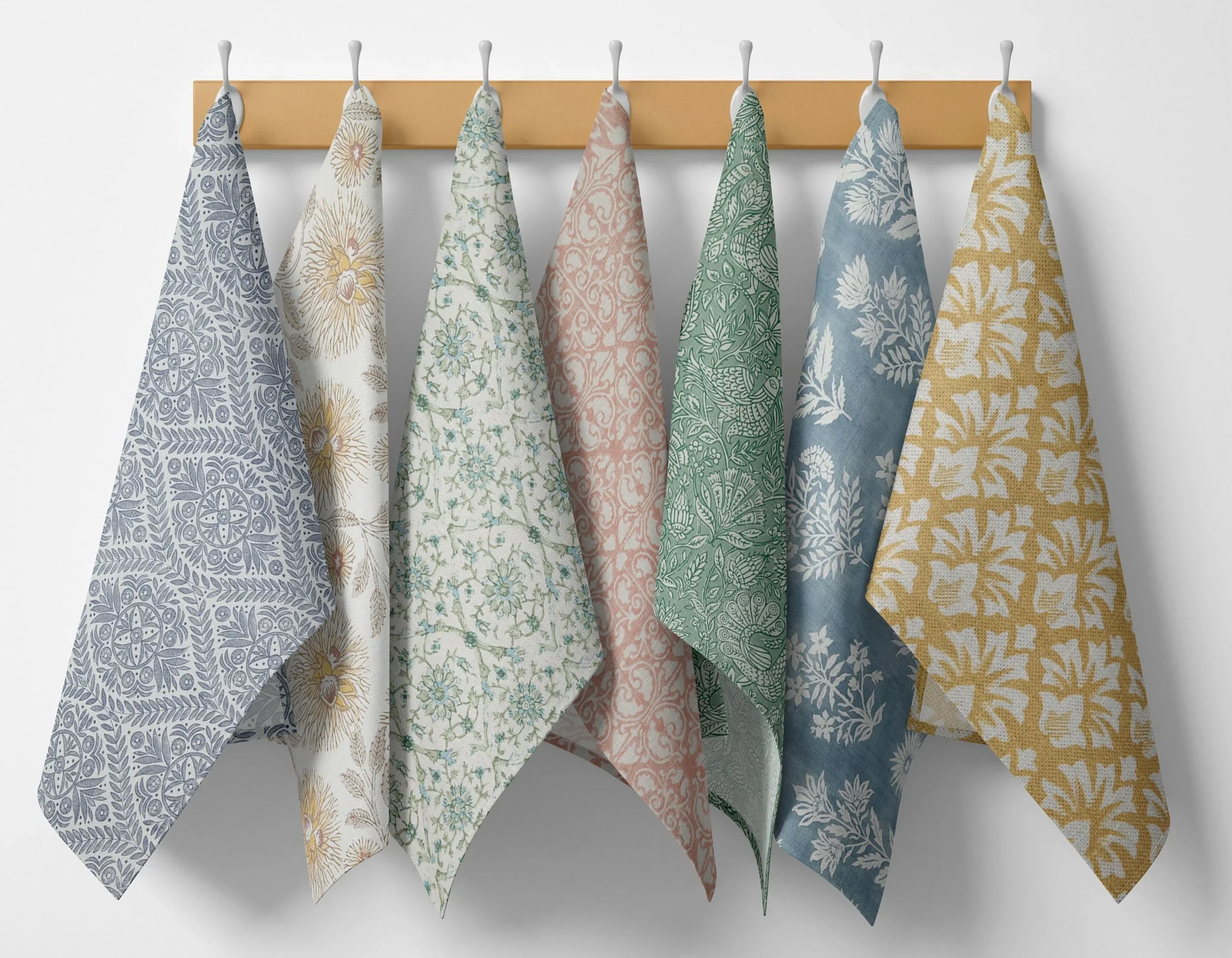 Multiple patterned towels hanging on a wooden rack against a white background.