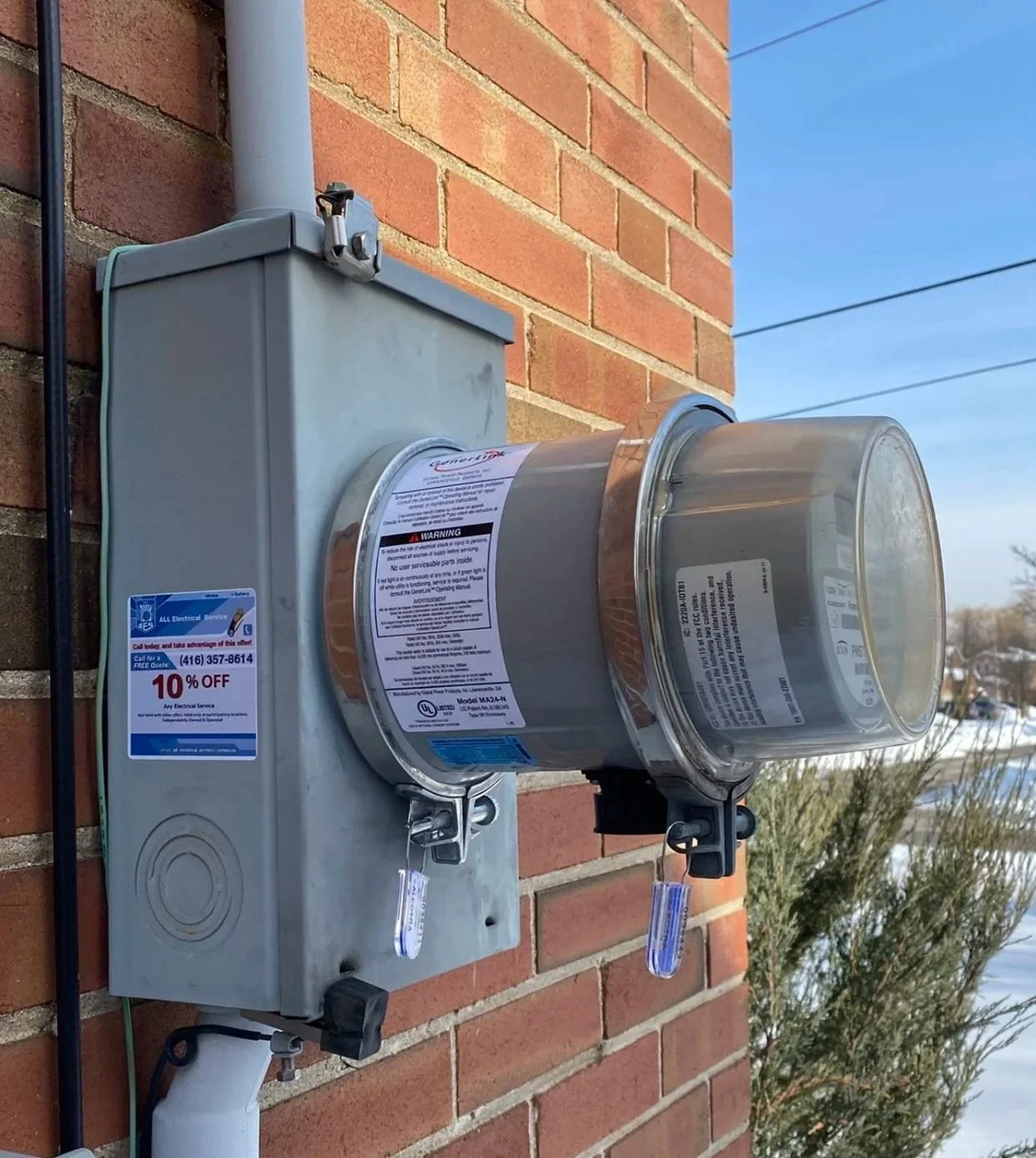 GenerLink generator transfer switch and electric meter equipment professionally installed on a brick wall.