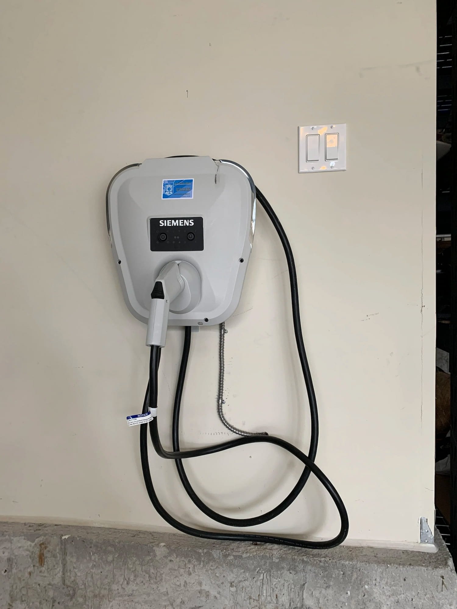 Professional installation of a Siemens EV charging station with AES logo on a residential garage wall.