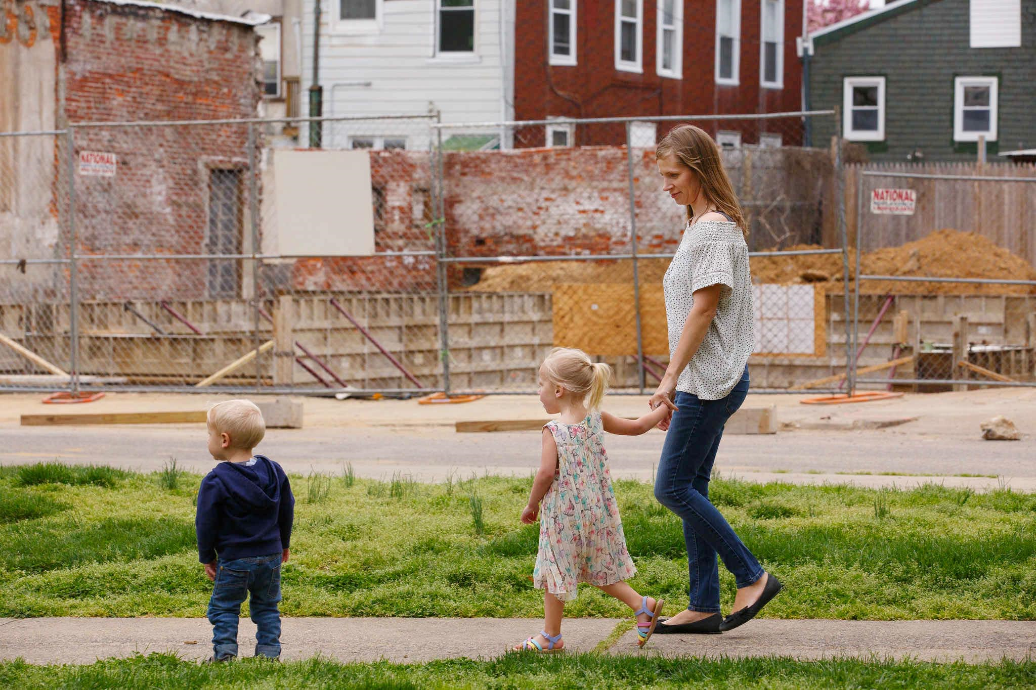 Jana Curtis and two of her children walk past one of many construction sites in their river ward neighborhood. Three-year-old Nolyn Pace, center, was poisoned by lead in the soil in their backyard