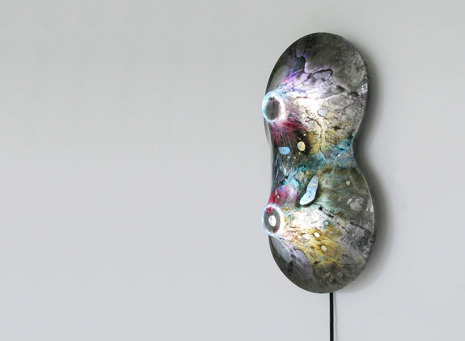 The Nuclei Lamp by Taeg Nishimoto boasts a warping surface made of two layers of polyolefin film (or shrink wrap) within which are sandwiched a combination of paints of various fluidity. The application of heat and light on the film creates unexpected interactions among the paints as well as with trapped air inside the layers, leading to the visual effects seen above.