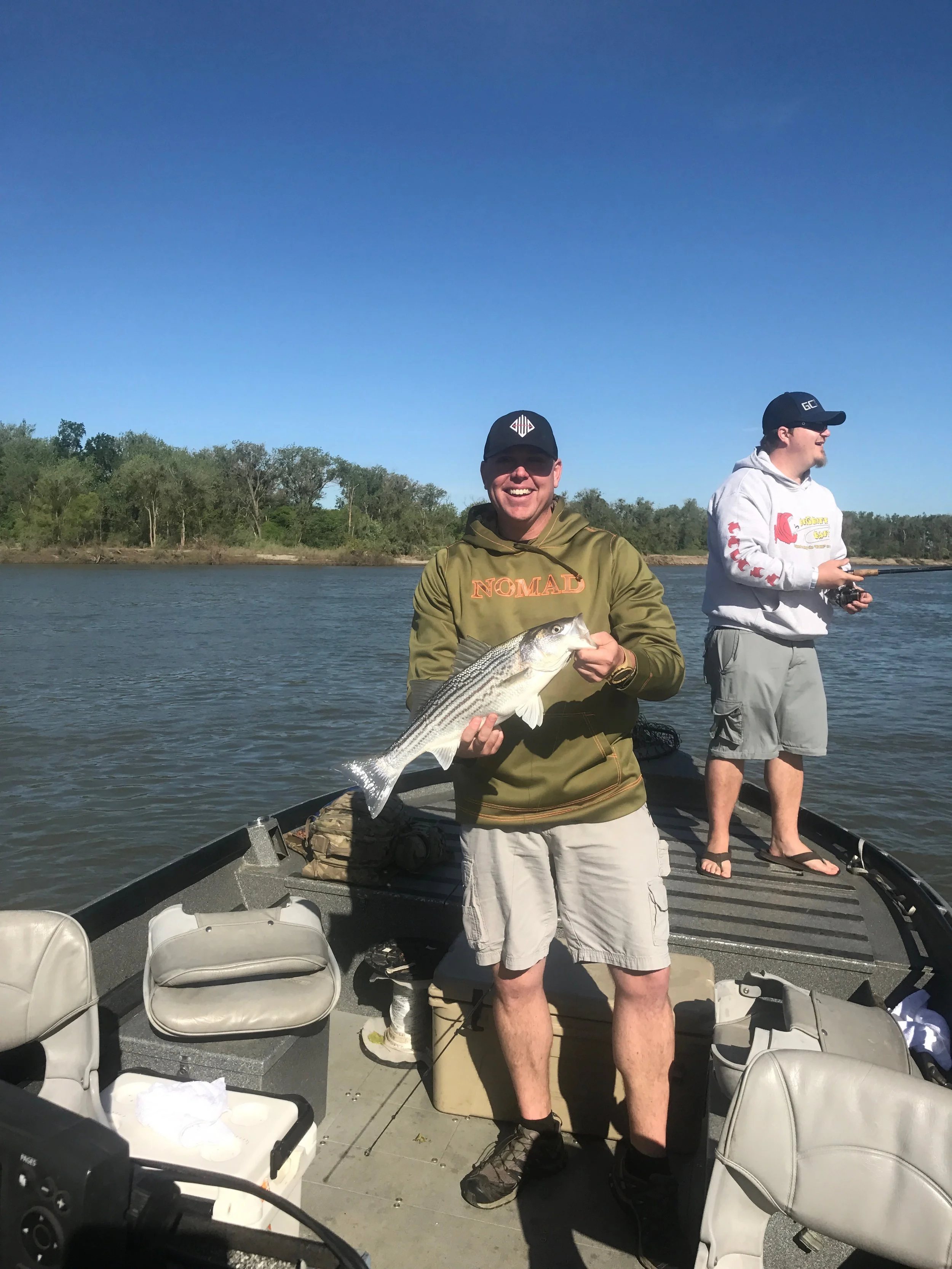 Pictured is Corning, Ca Chief of Police Jeremiah Fears with a quality striped bass he caught while casting swim baits at gravel bars along the Feather River near Yuba City, Ca. Nick Kanabrocki is casting in the background of the photo.