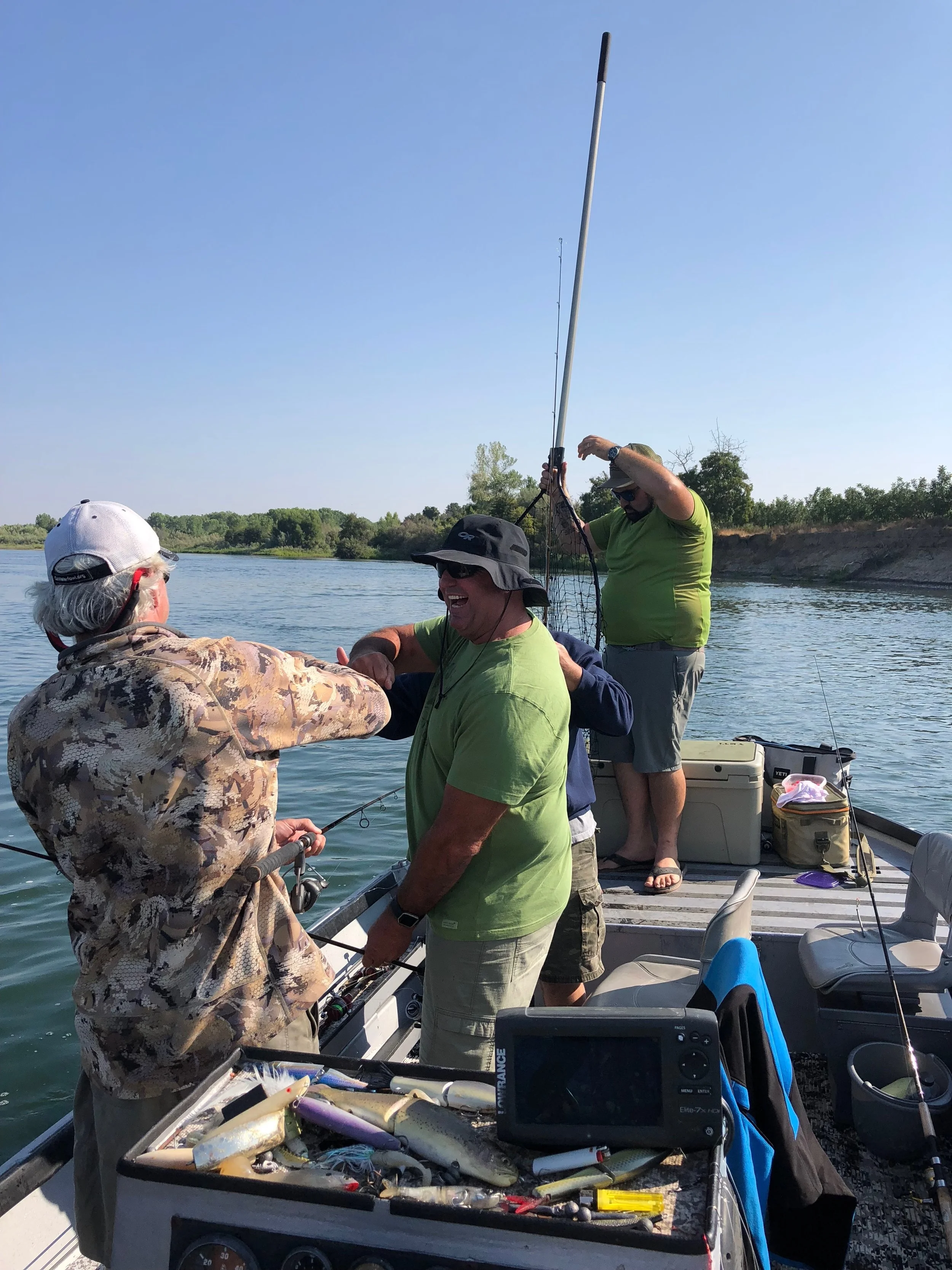 Fist bumps exchanged after landing a big chinook salmon on the Sacramento River with fishing guide Mike Rasmussen. The group was fishing Woodson Bridge boat launch near Corning, Ca when this picture was taken.&nbsp;