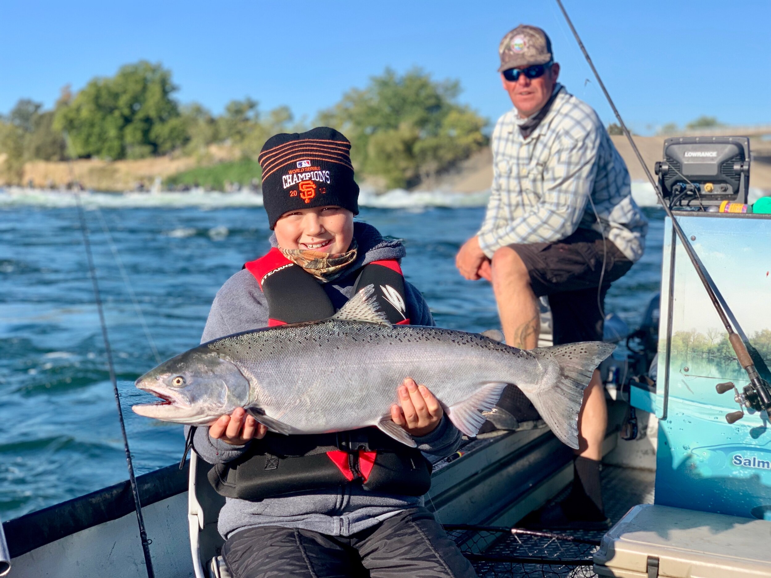 A happy young man holding his first ever king salmon he caught on the Feather River with fishing guide Ryan Tripp.