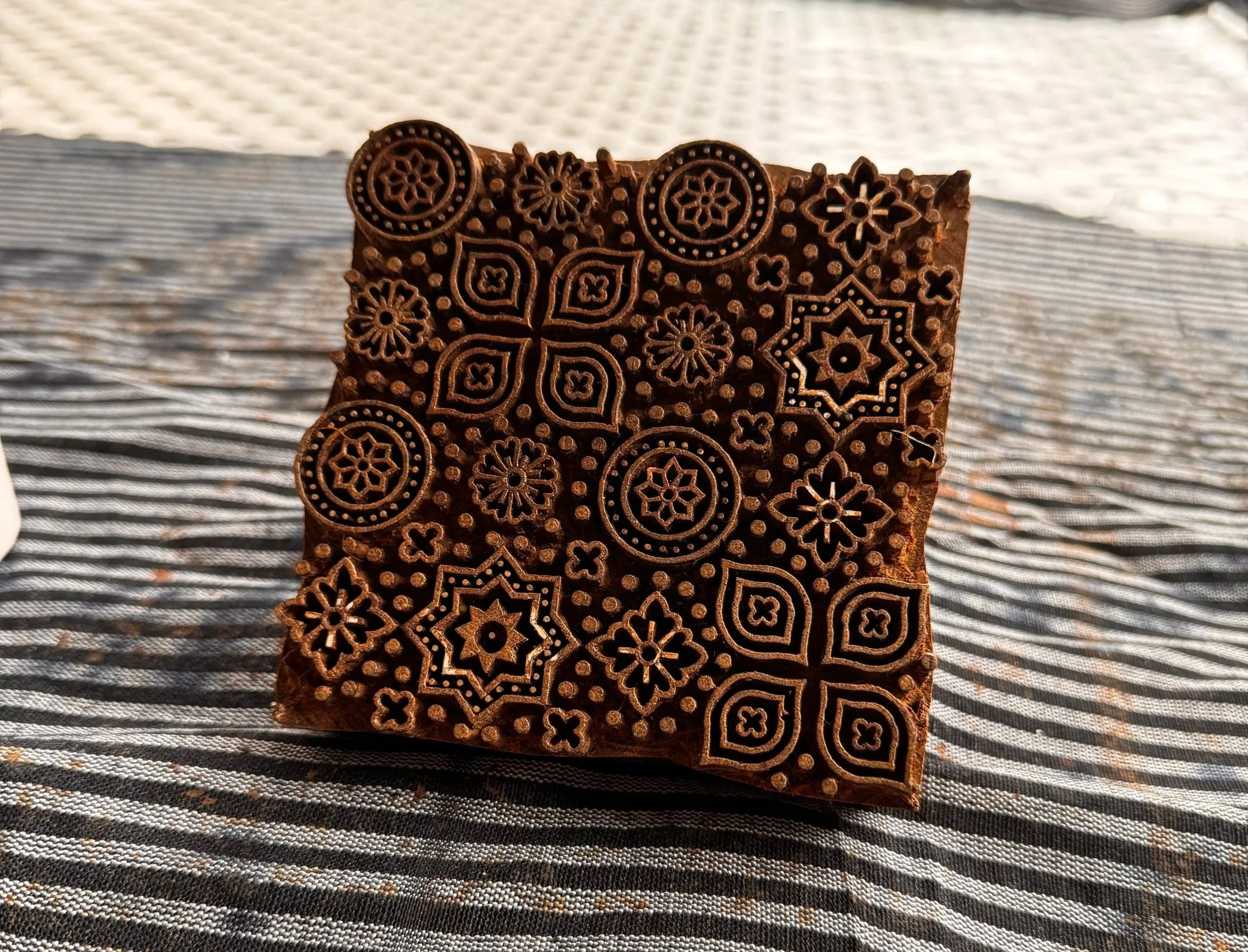 Carved teak wood block resting on fabric
