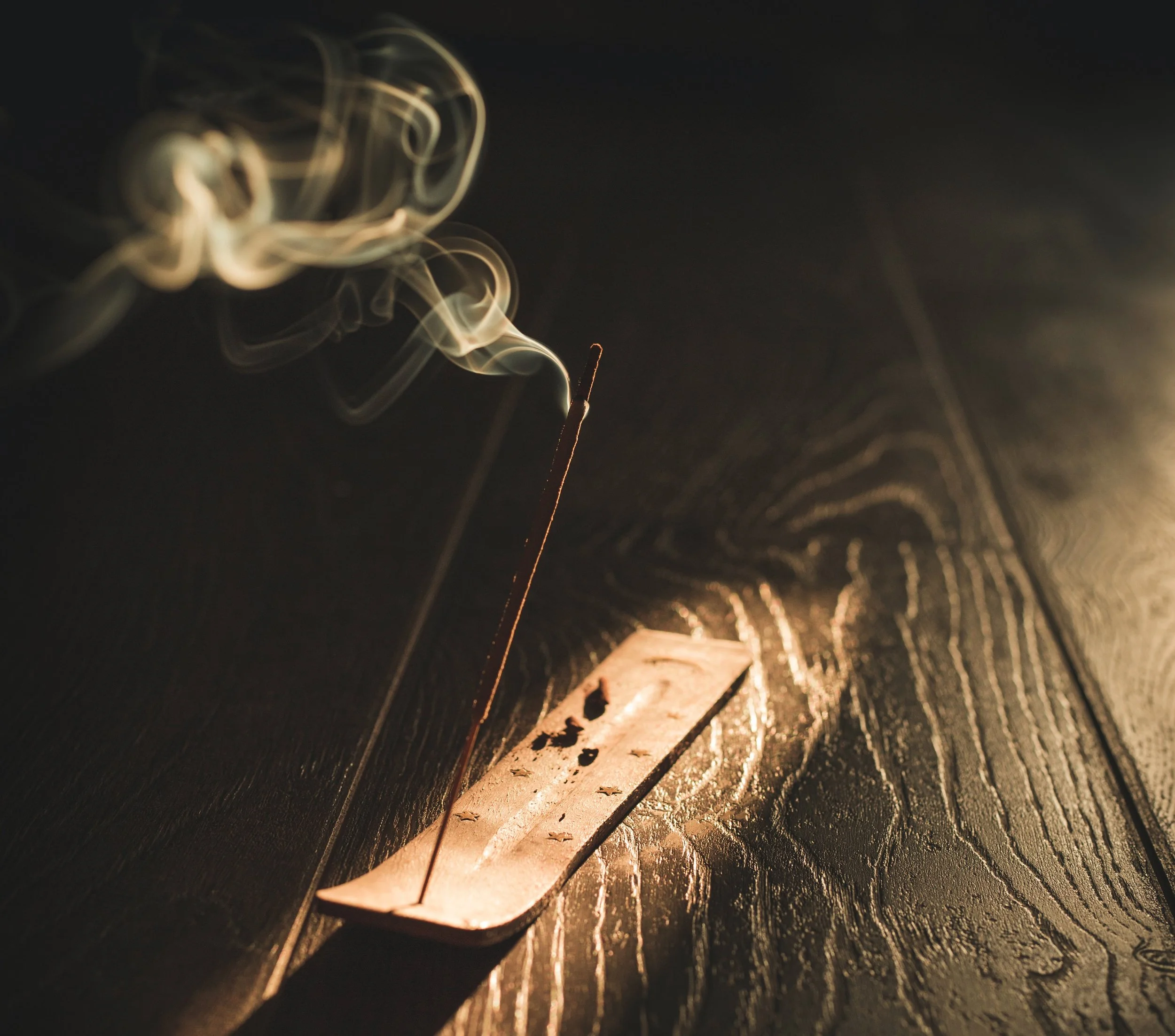 Dark mood photo showing lit incense stick and smoke in incense holder