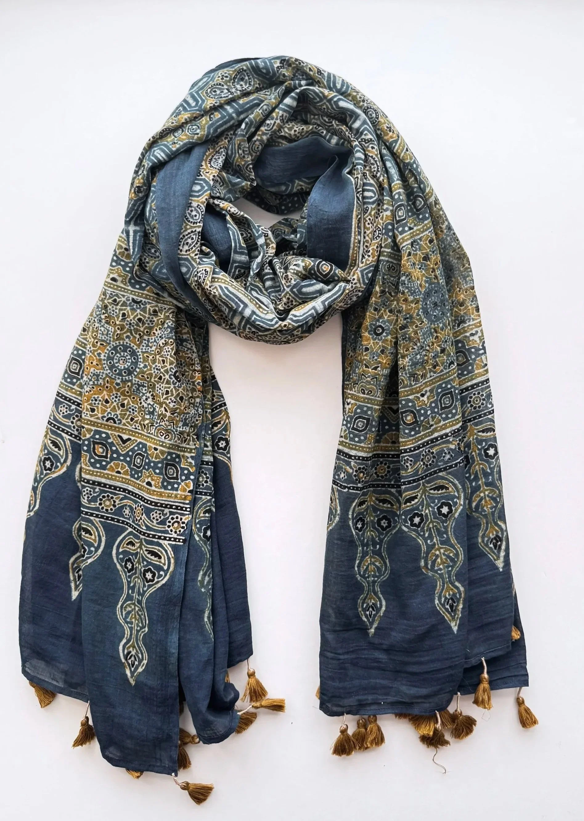 Handmade Indigo and olive Ajrakh block print cotton shawl with mustard tassels, draped on a white background