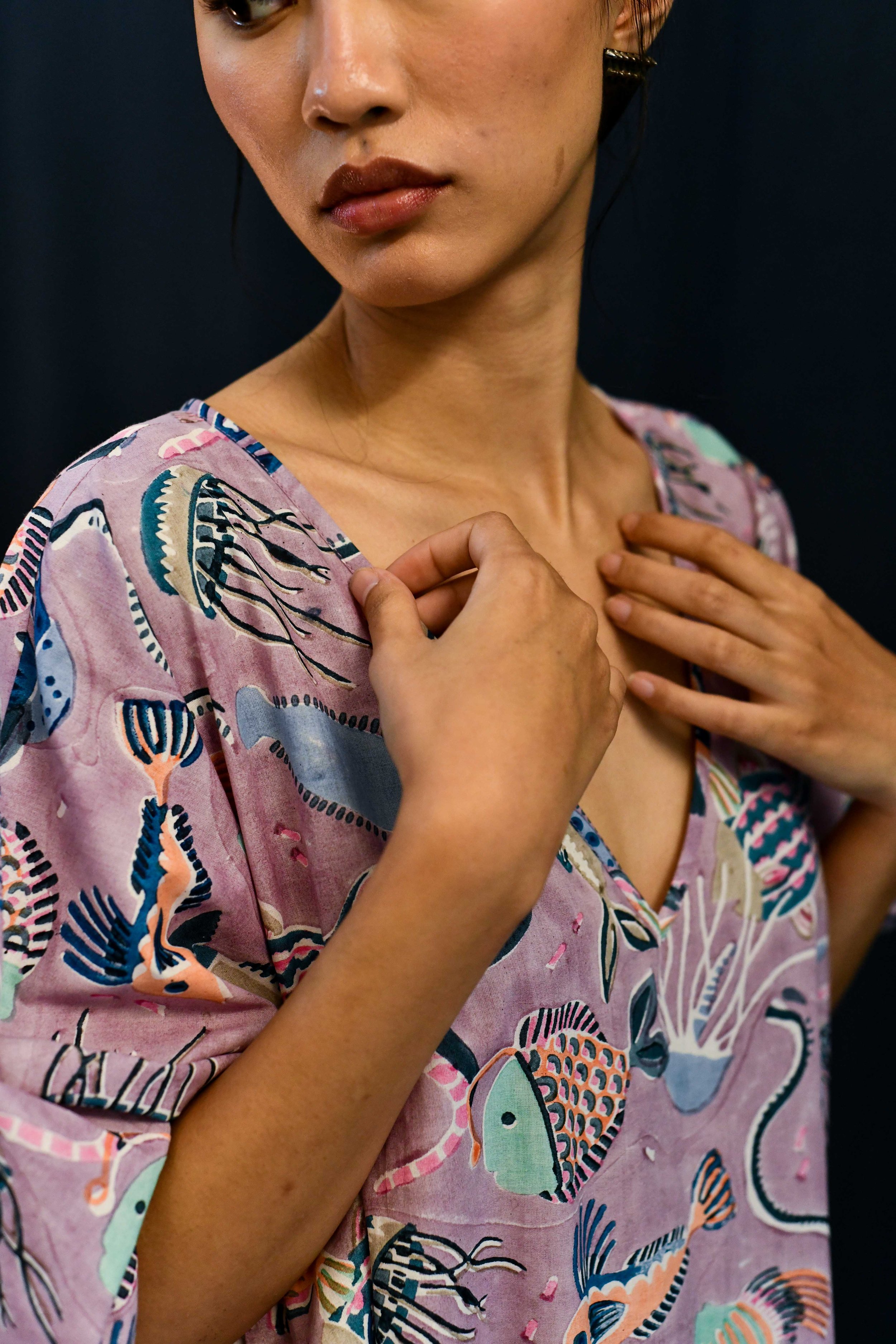 close up image of model wearing a multicoloured kaftan dress with a sea life print