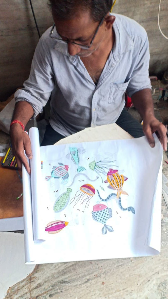 Indian artisan holding colourful drawings of nautical print for process of hand block printed cotton kaftans