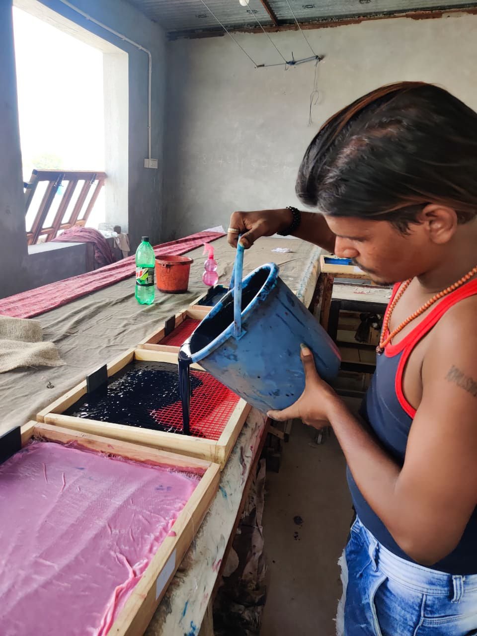 Indian artisan pouring colourful dyes into wooden containers