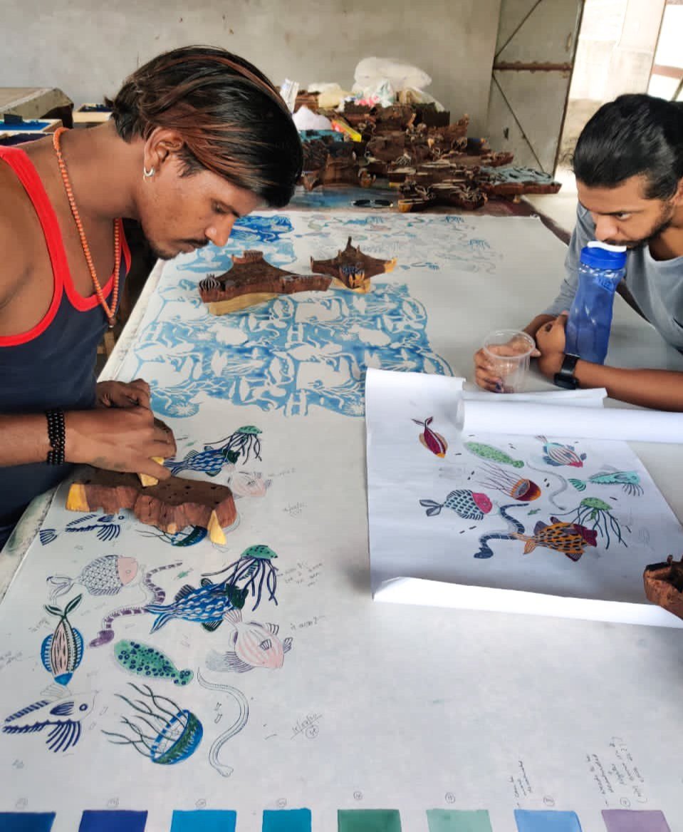 Two indian artisans block printing nautical shapes onto white fabric