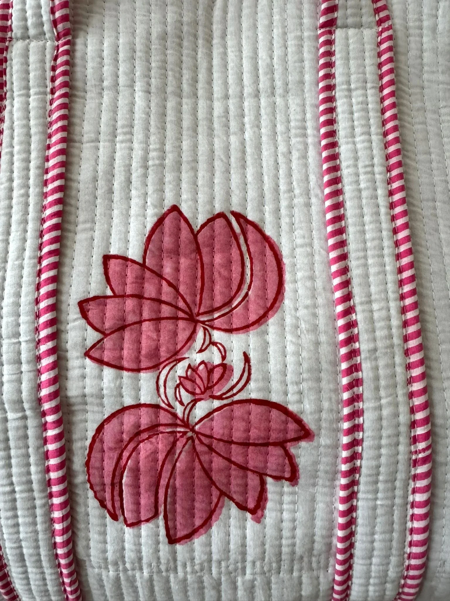 Close up of pink hand block printed flower on off-white quilted cotton tote bag