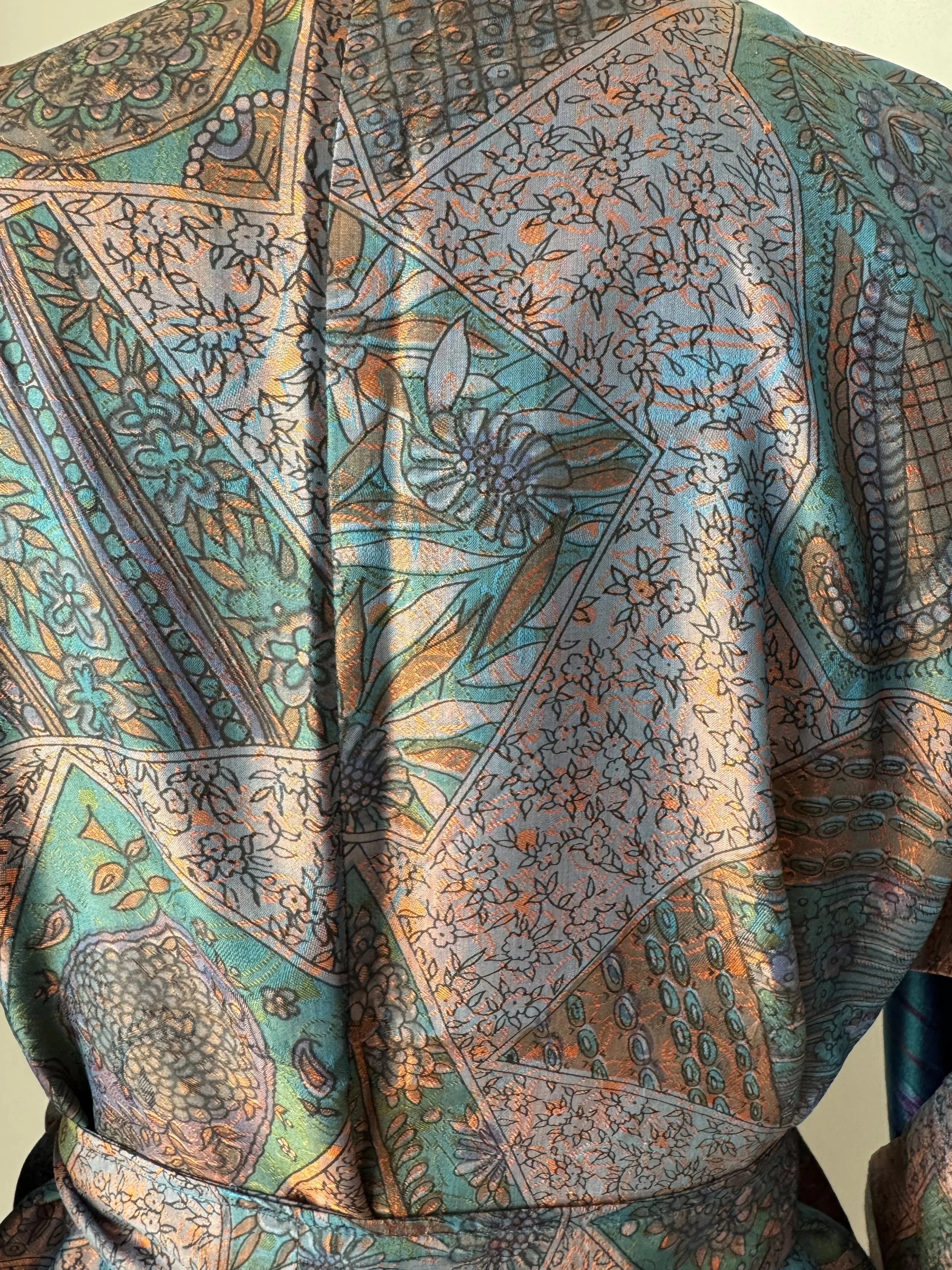 Close-up of two-tone shot silk fabric showing aubergine and orange floral pattern, upcycled sari silk