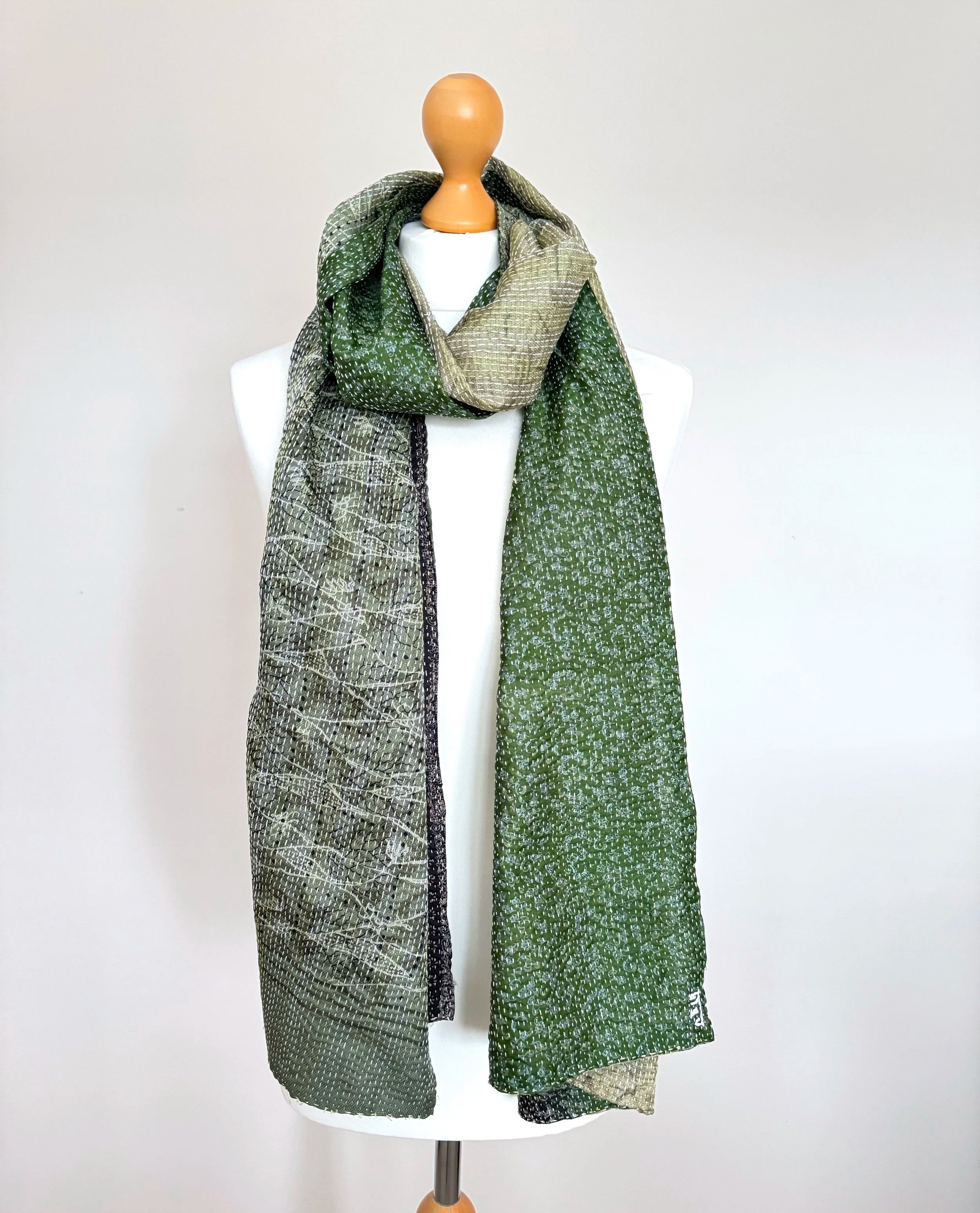 Long green upcycled sari silk scarf draped around a white mannequin, handmade from recycled sari silk and embroidered with Kantha stitch all over to give a lightly quilted effect.