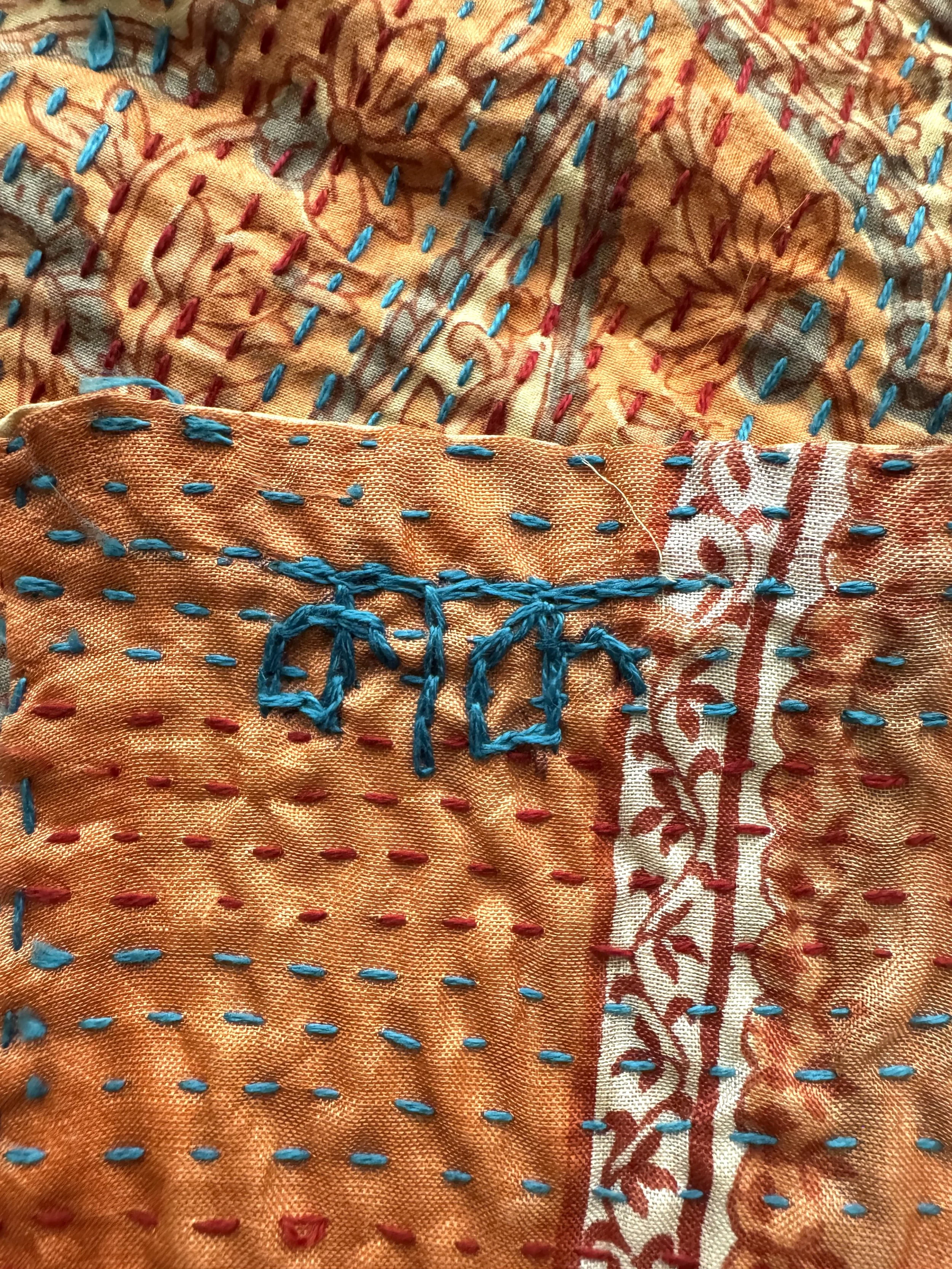 Colourful hand embroidered name of Kantha artisan maker on orange upcycled sari silk
