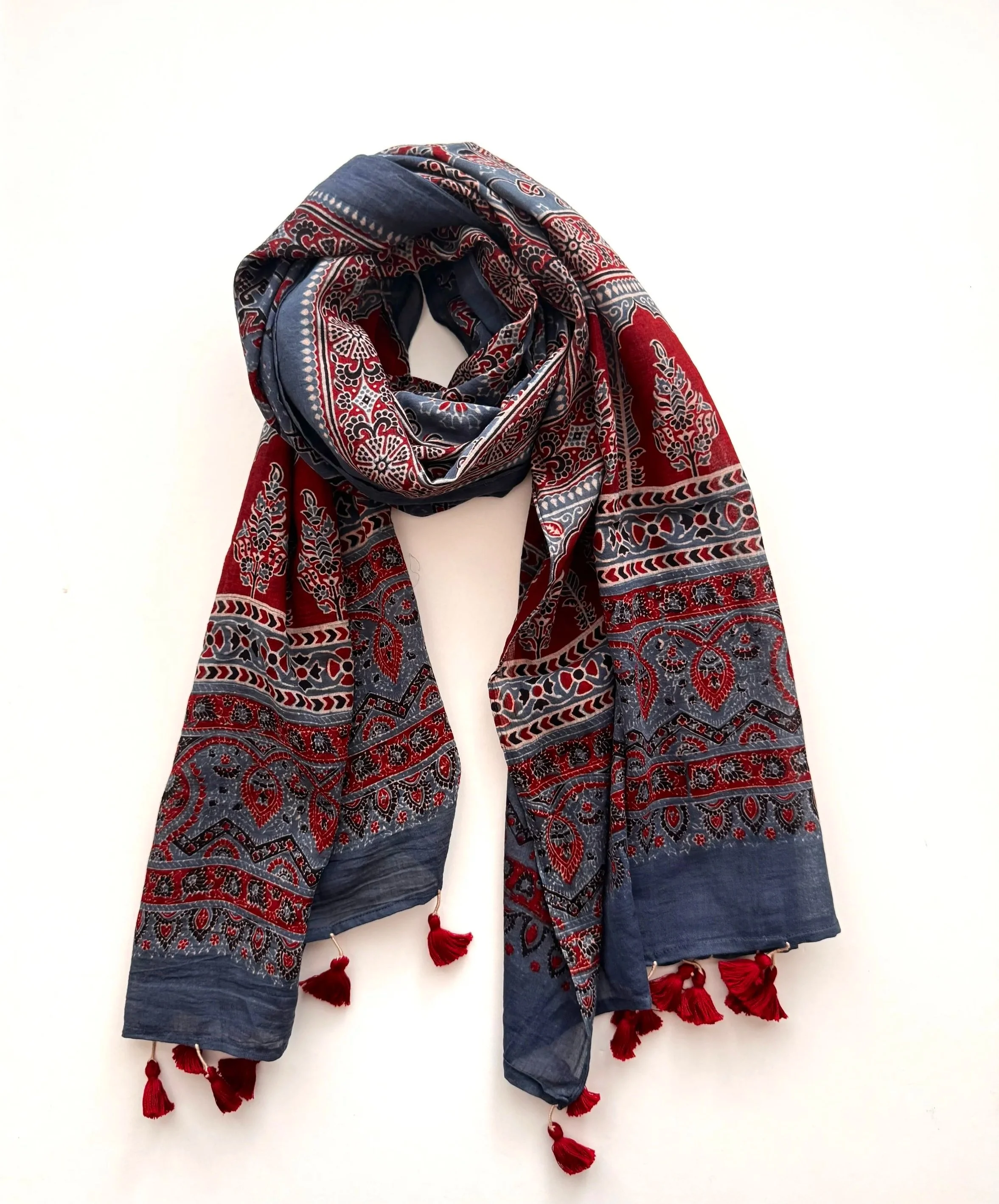 Indigo and red Ajrakh block print cotton scarf with red tassels, draped on a white background