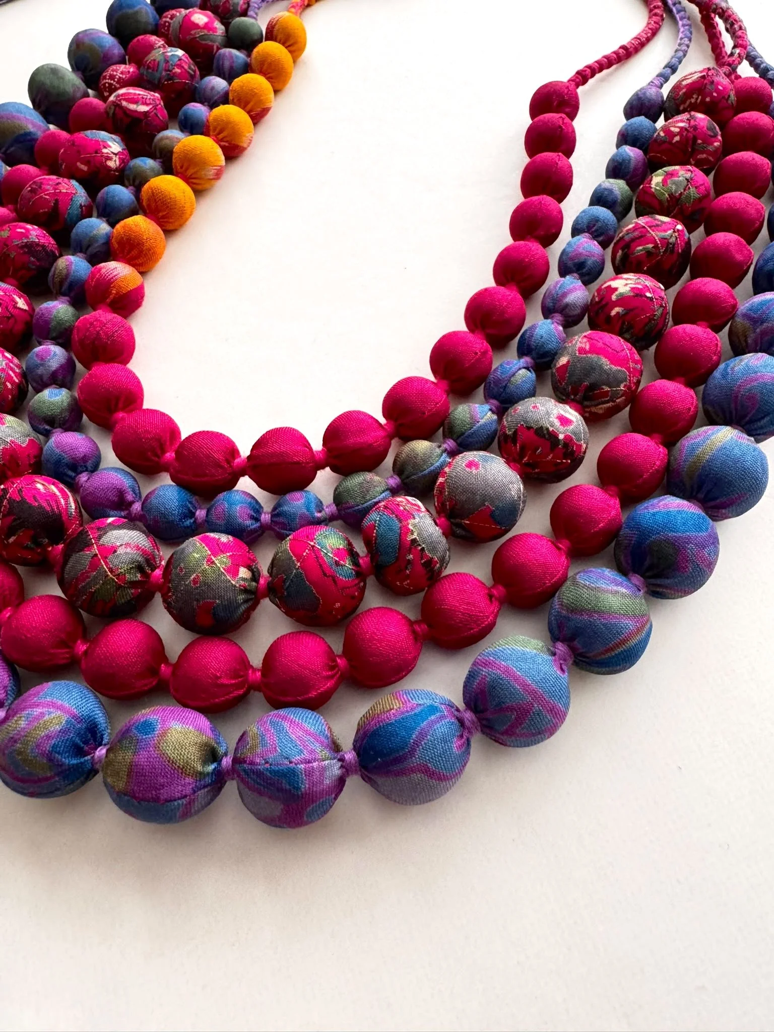 Close up colourful upcycled sari silk beaded necklace on a white background
