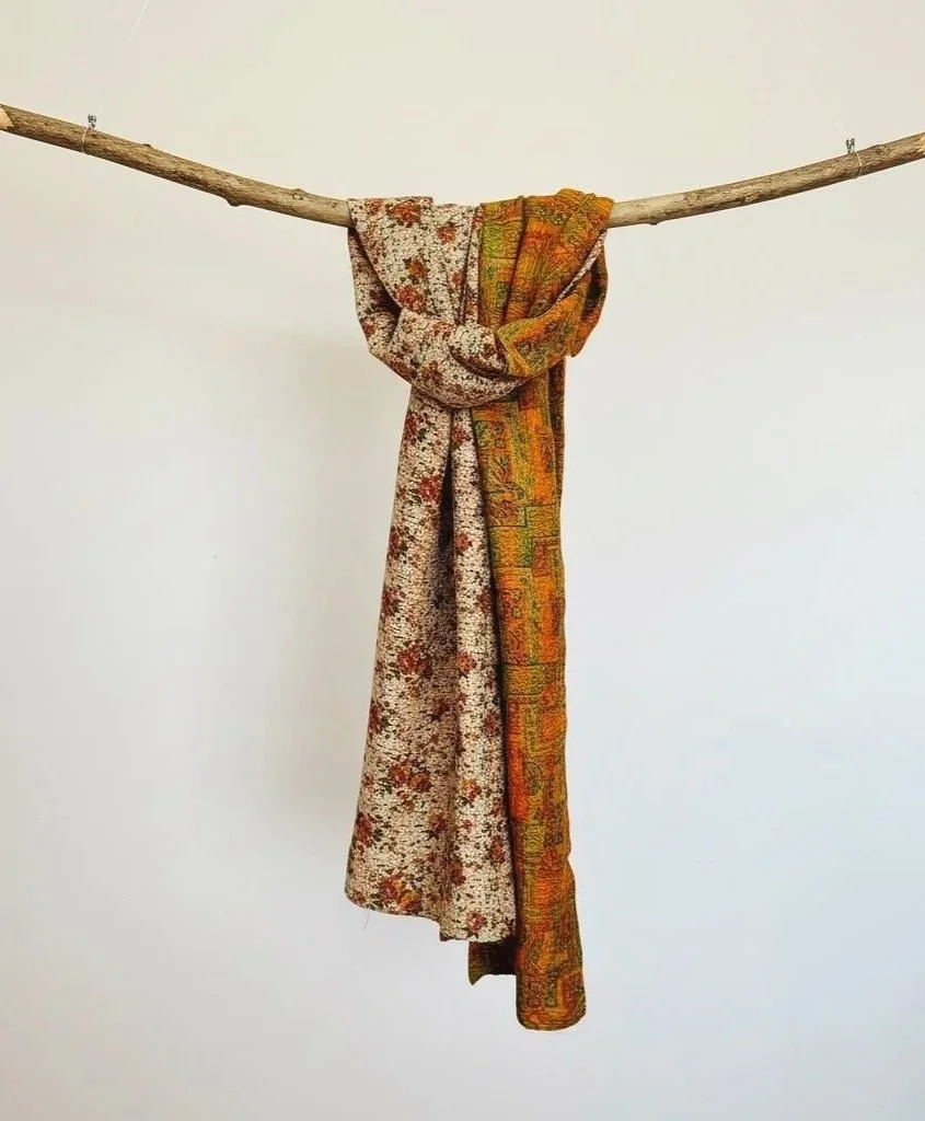 Colourful floral silk scarf with a reversible pattern hanging from a wooden branch against a white background
