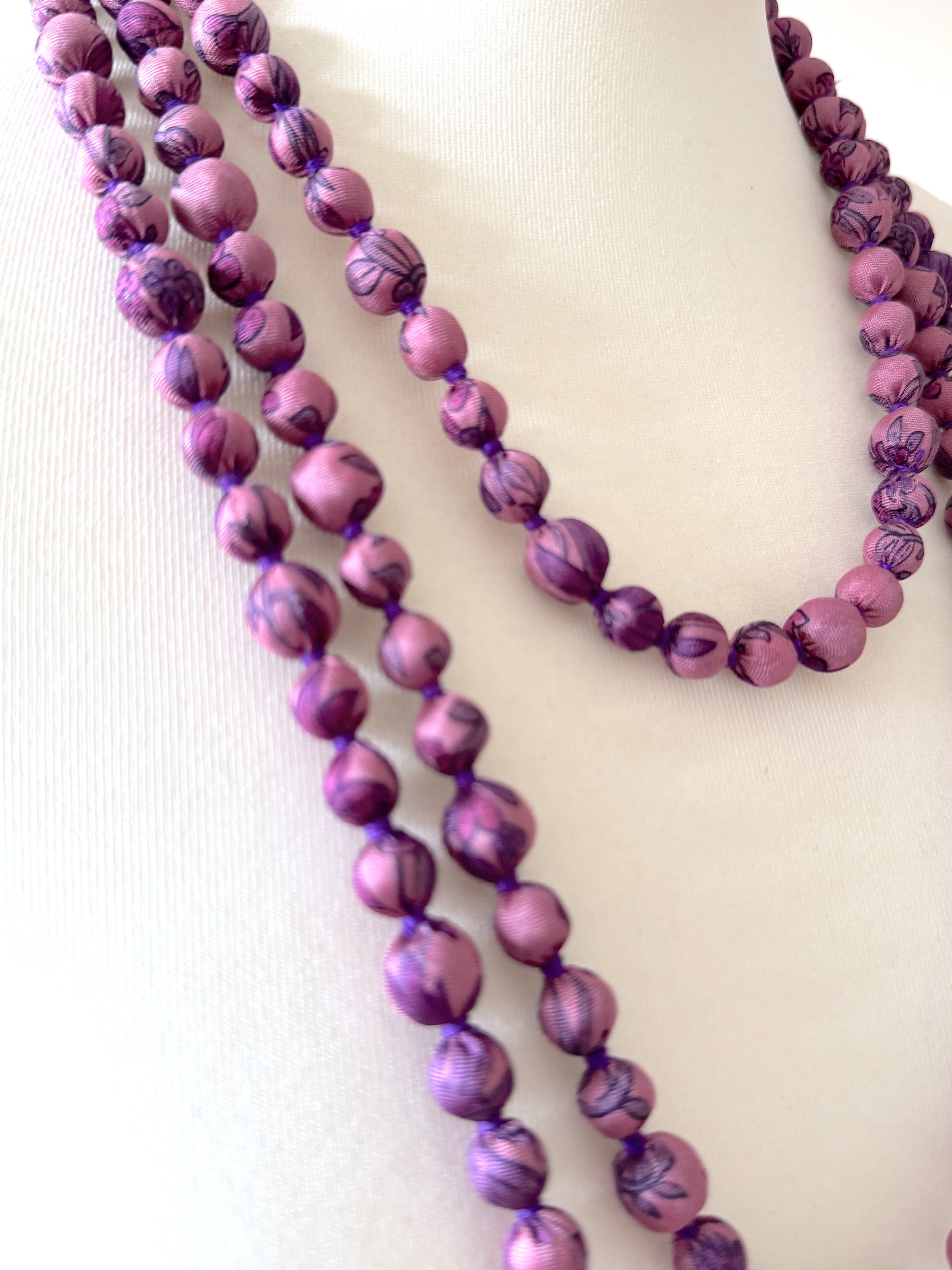 close up of purple handmade long bead sari silk necklace styled around a white mannequin