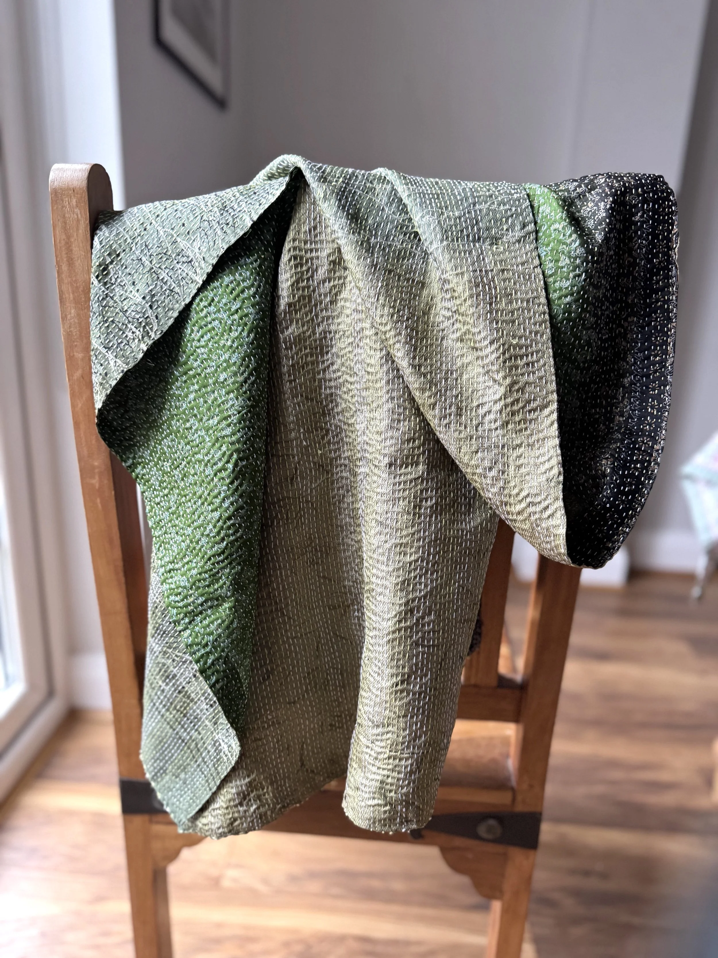 Reversible green recycled sari silk scarf in shades of emerald and olive draped over a wooden Jali style chair