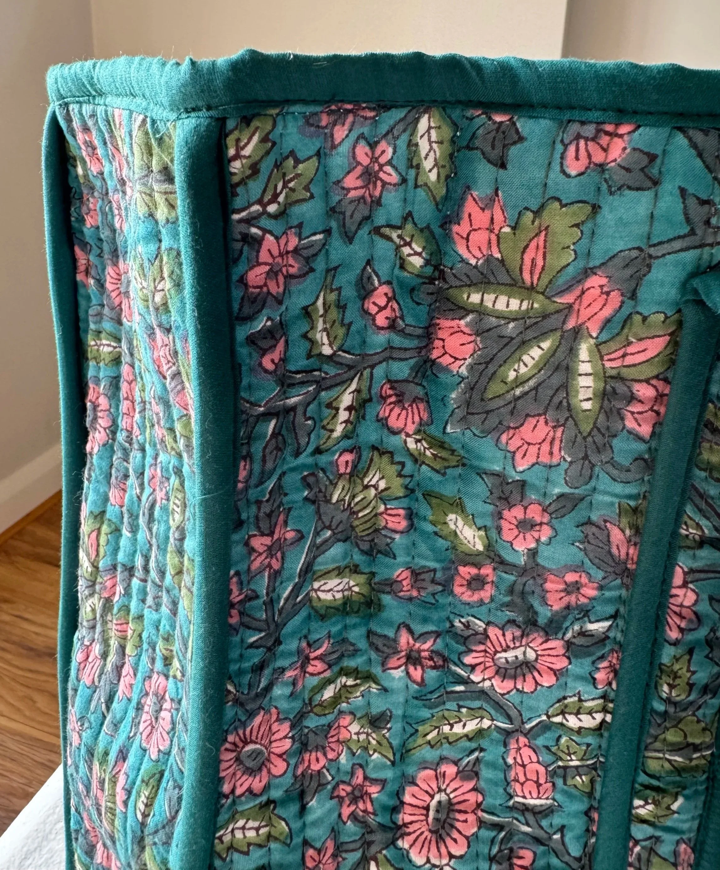 Close up of indian hand block printed floral design on a teal quilted tote bag.