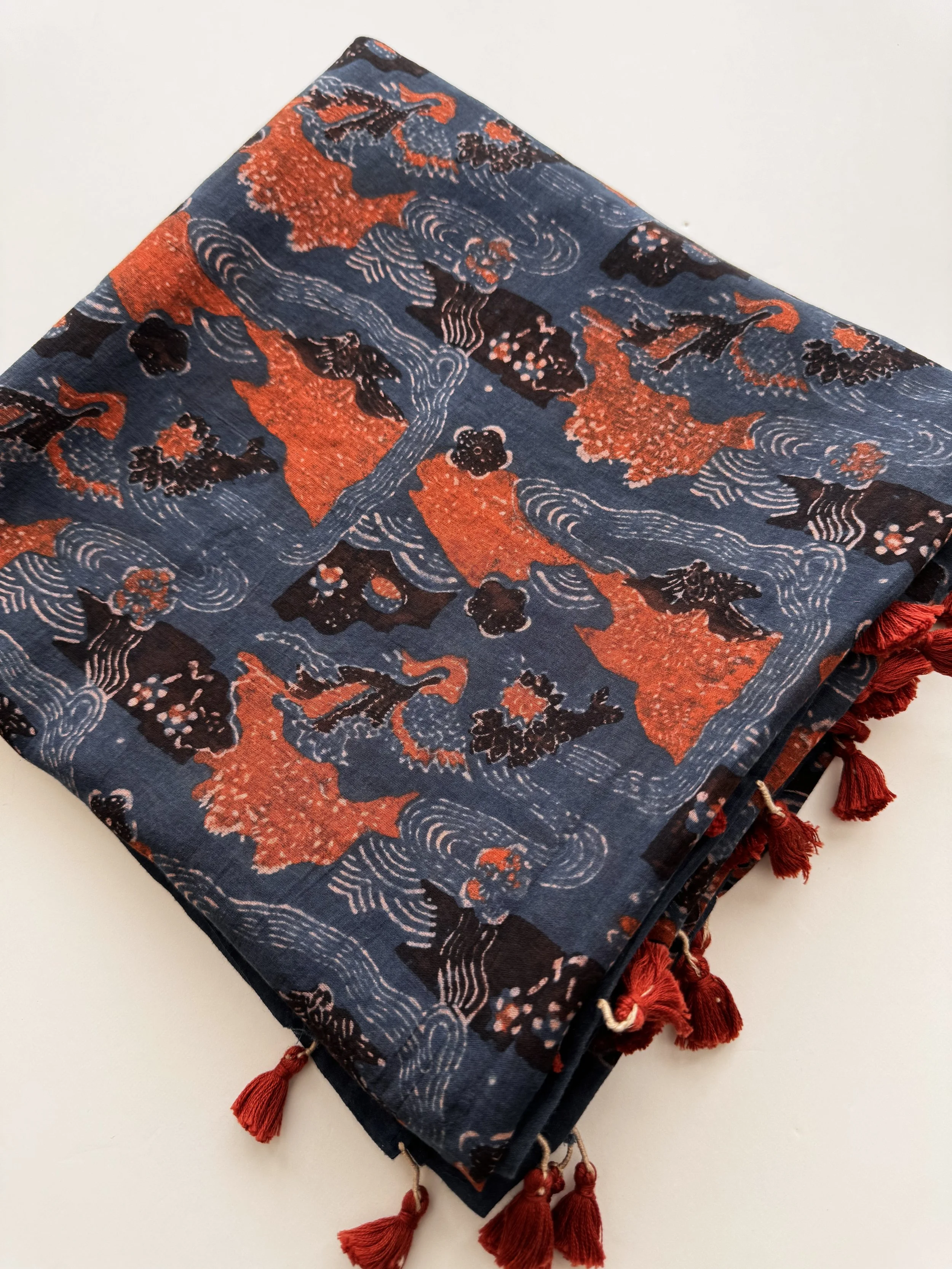 Folded indigo and rust red Ajrakh shawl showing wave and blossom print with red tassels