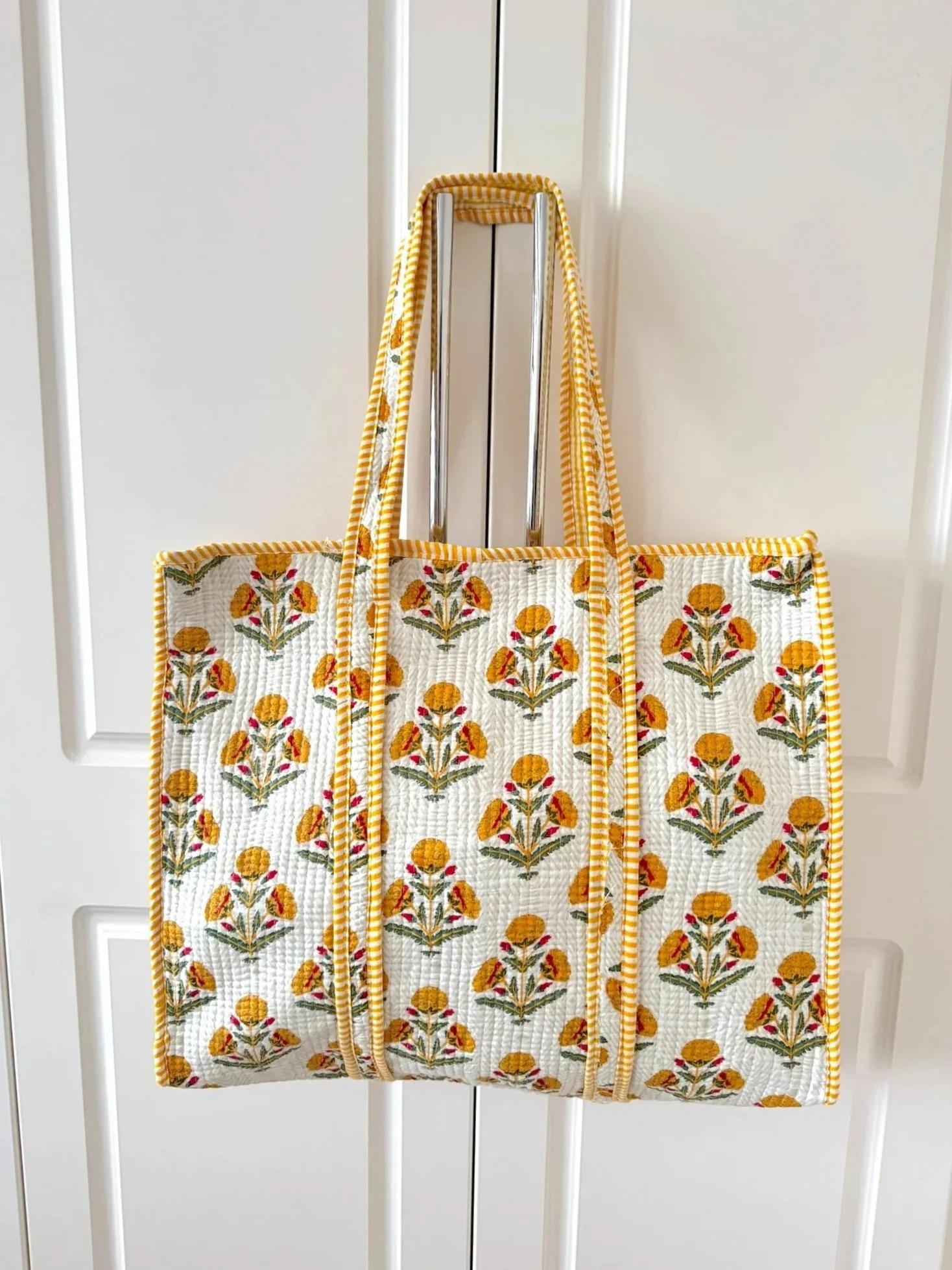 Yellow and white handmade Jaipur print quilted cotton beach tote for women hanging on a wardrobe handles
