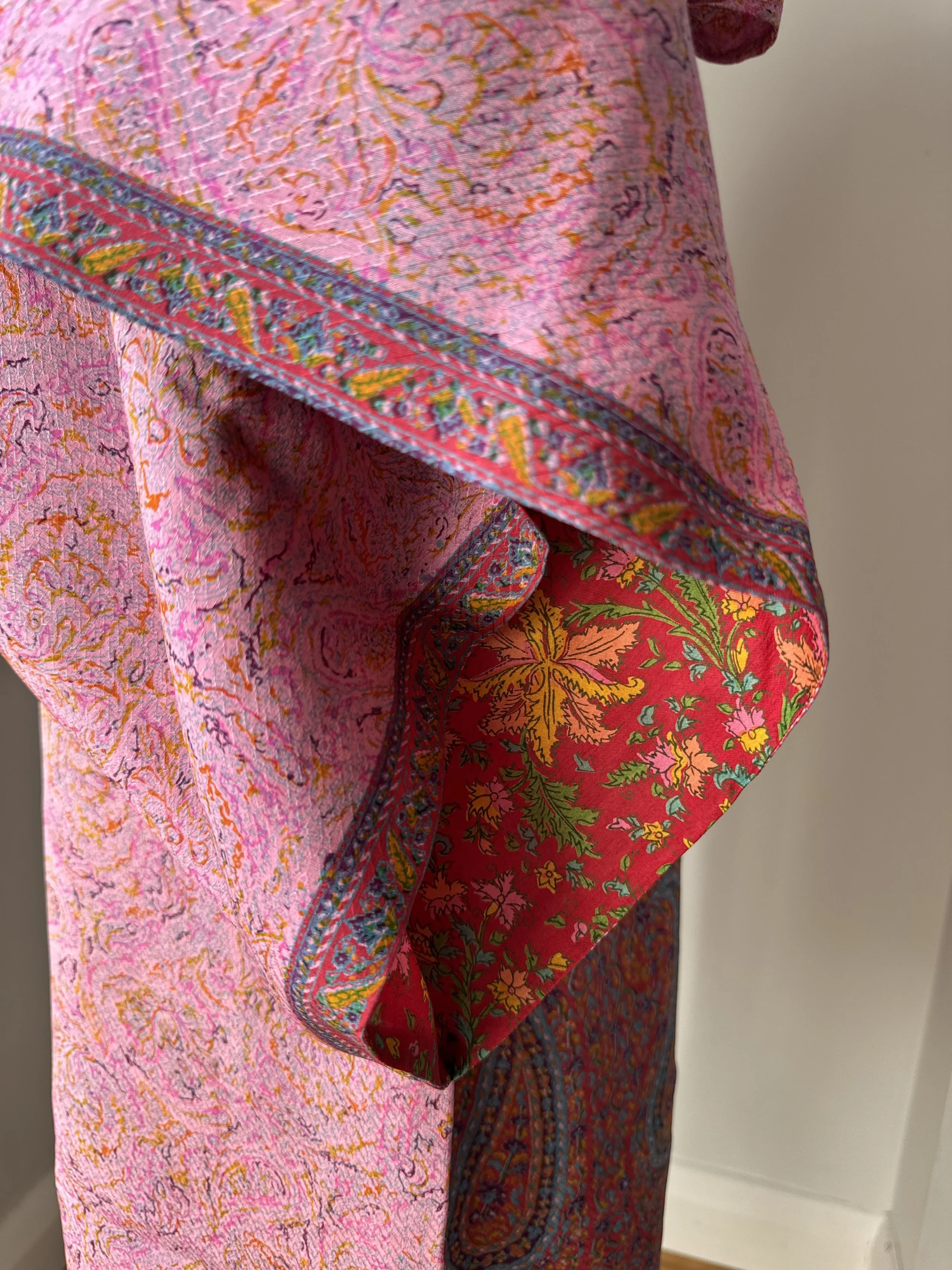 Close up of pink silk kimono sleeves with contrasting colourful floral lining in red, yellow, pink and green and striking border