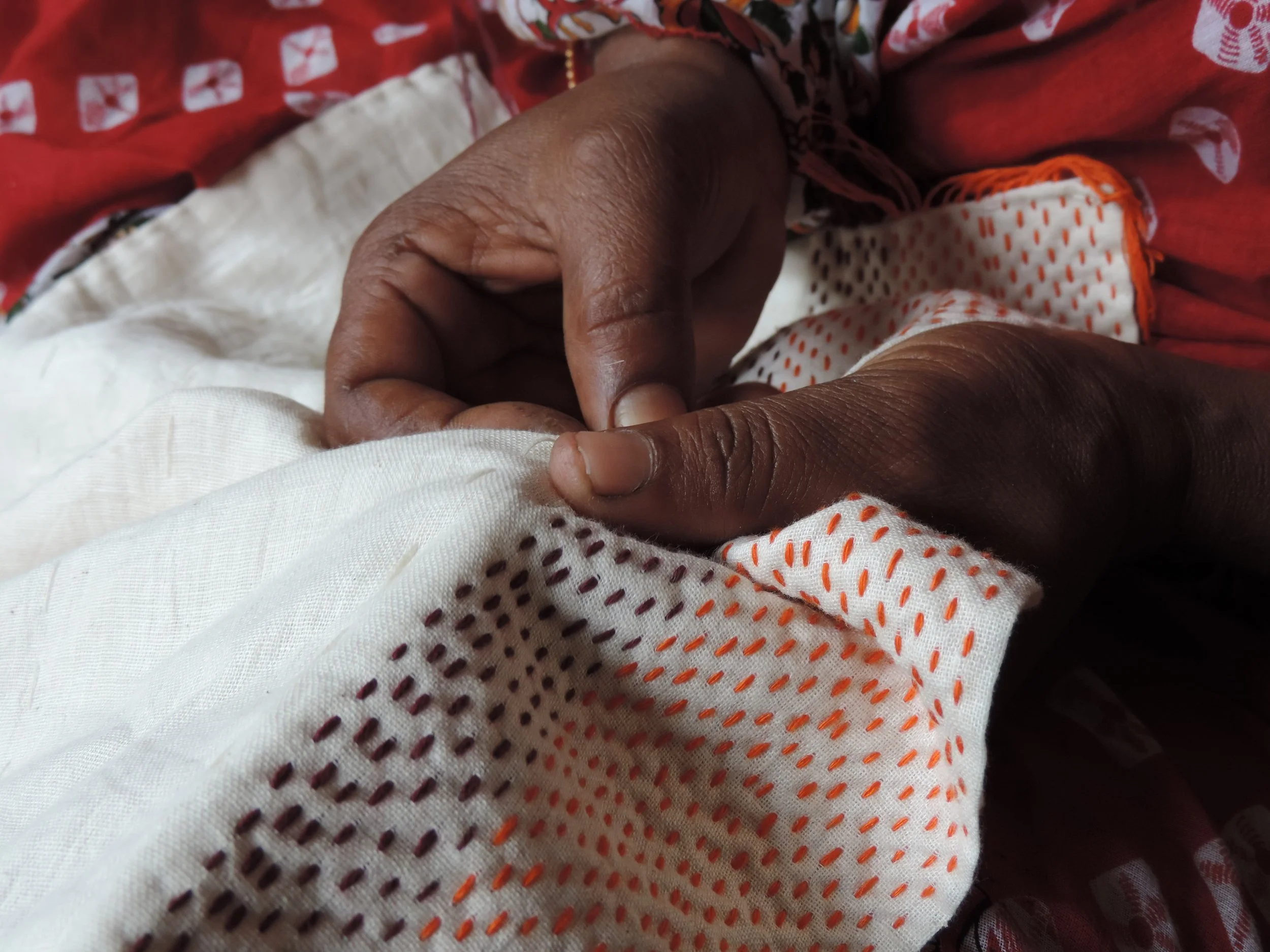 Artisan hands stitching kantha running on upcycled sari silk