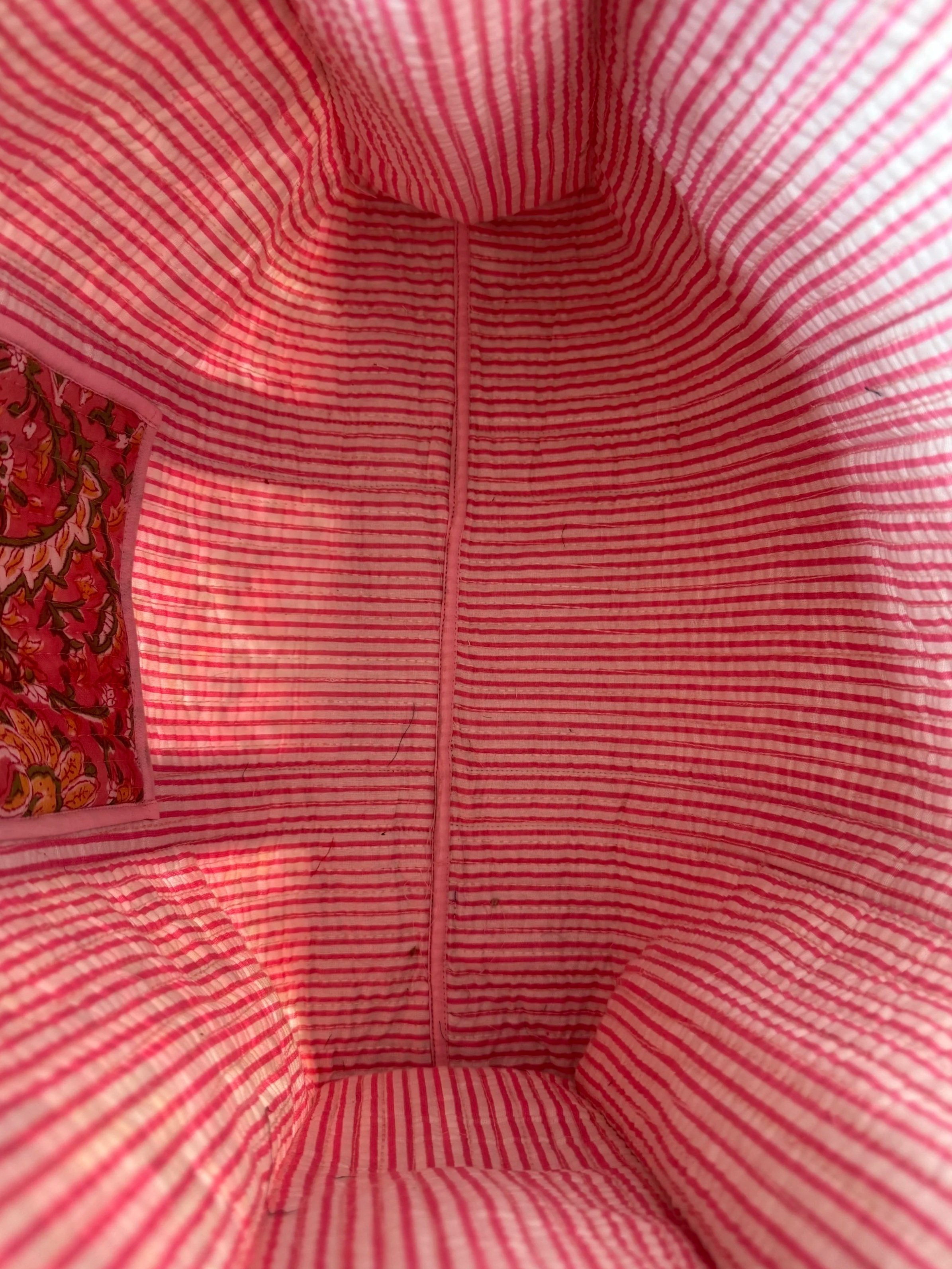 Inside of large handmade quilted tote bag with striped inside lining and floral inside pocket
