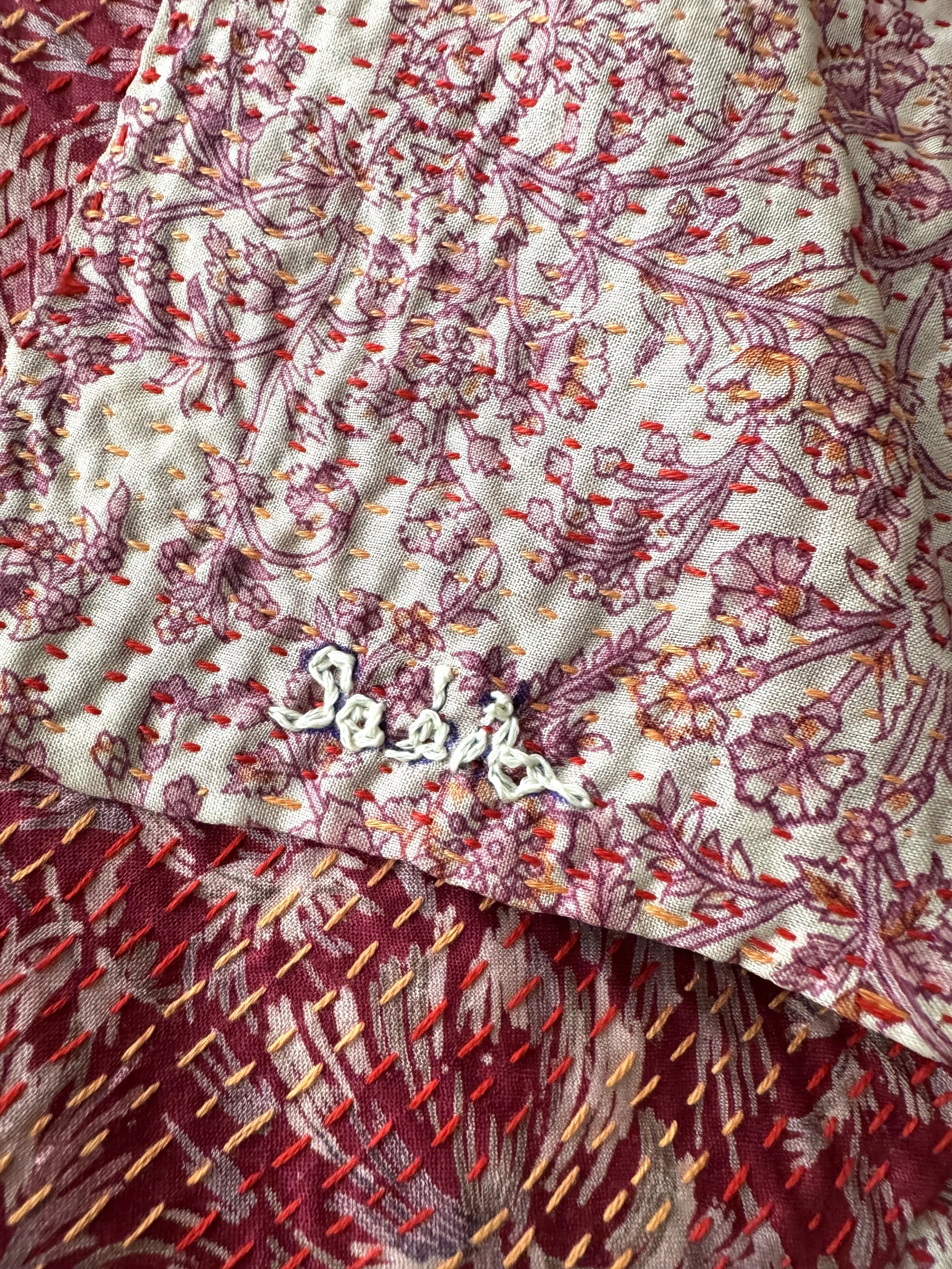 Close up of kantha stitch and embroidered name of artisan on floral print sari silk fabric