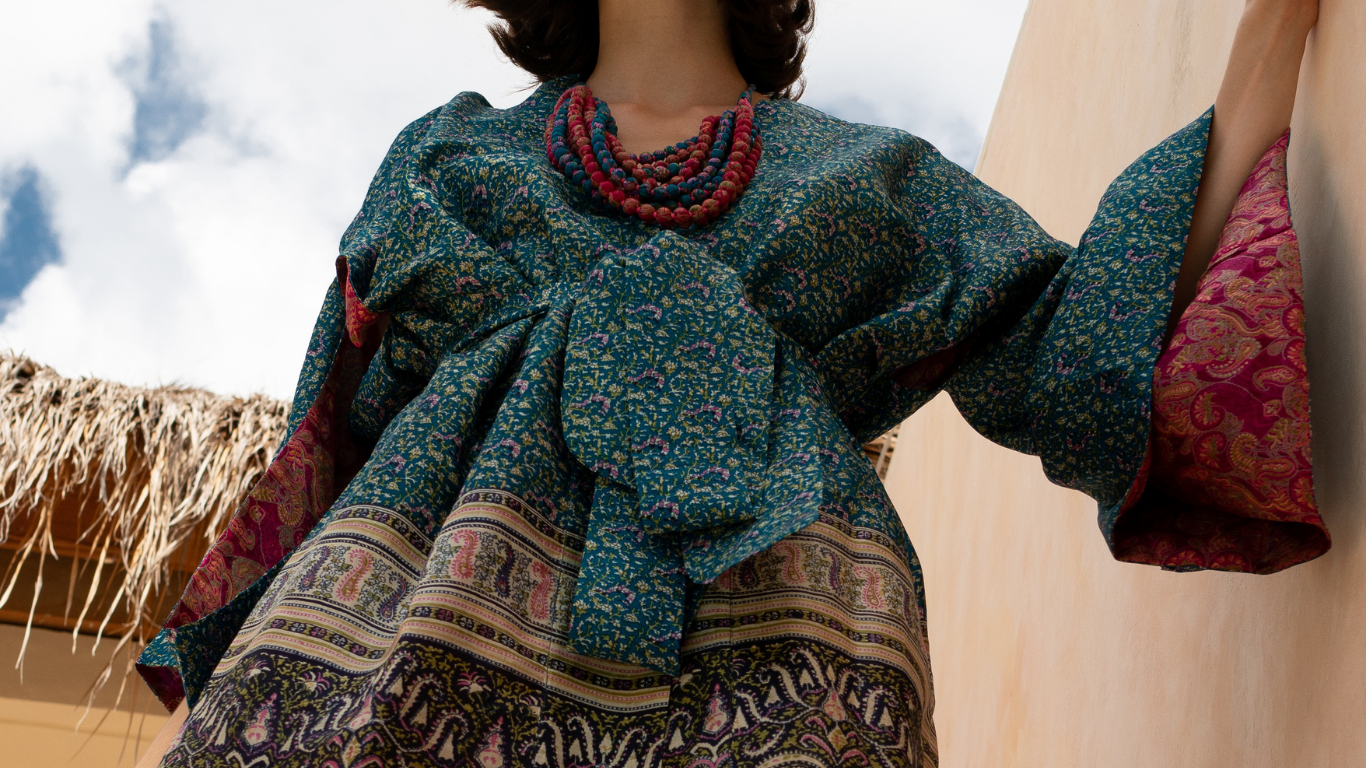 Woman wearing a colourful blue and pink upcycled sari silk kimono robe with matching pink and blue sari bead necklace