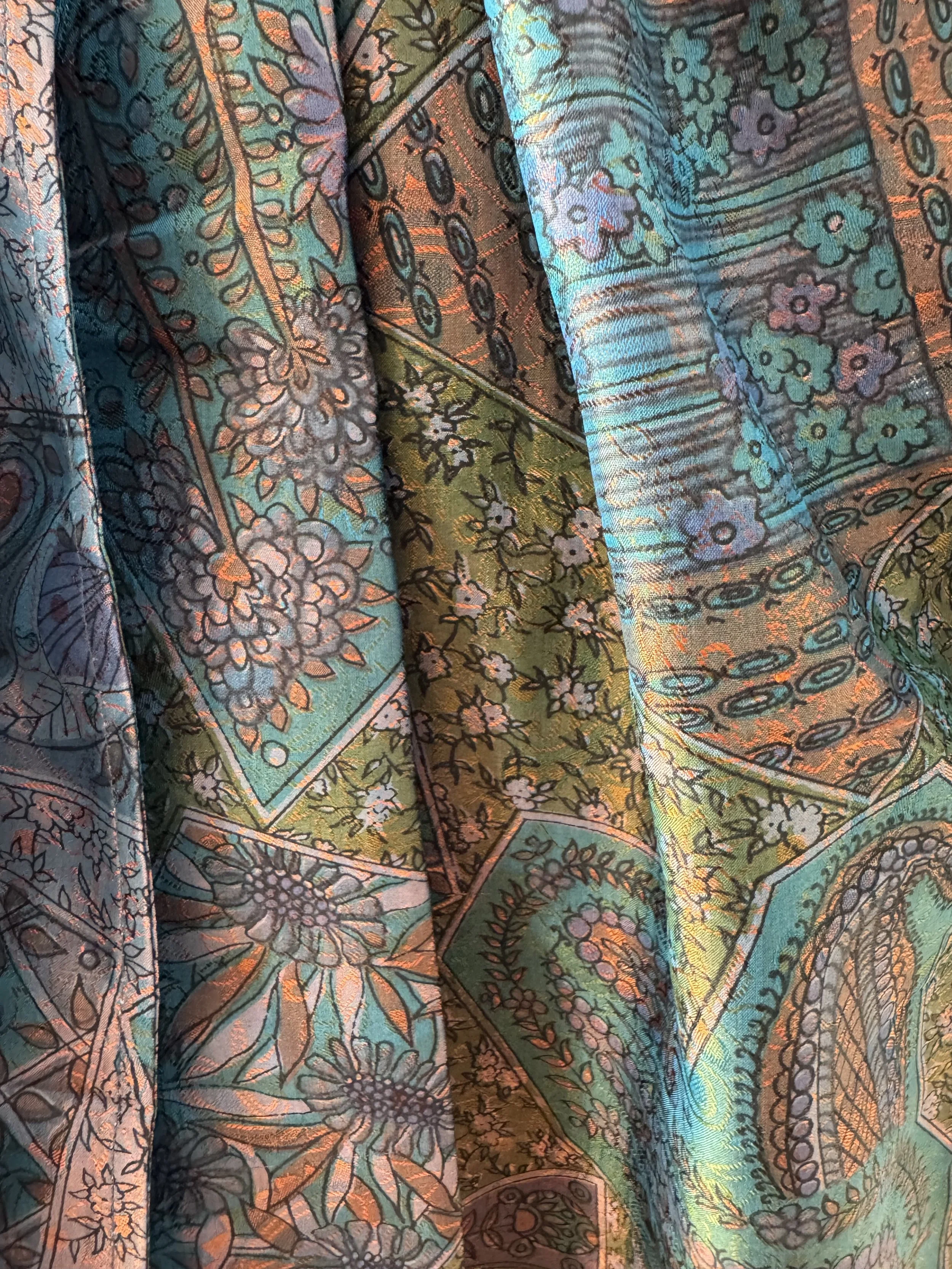 Close-up of two-tone shot silk fabric showing aubergine and orange floral pattern, upcycled sari silk