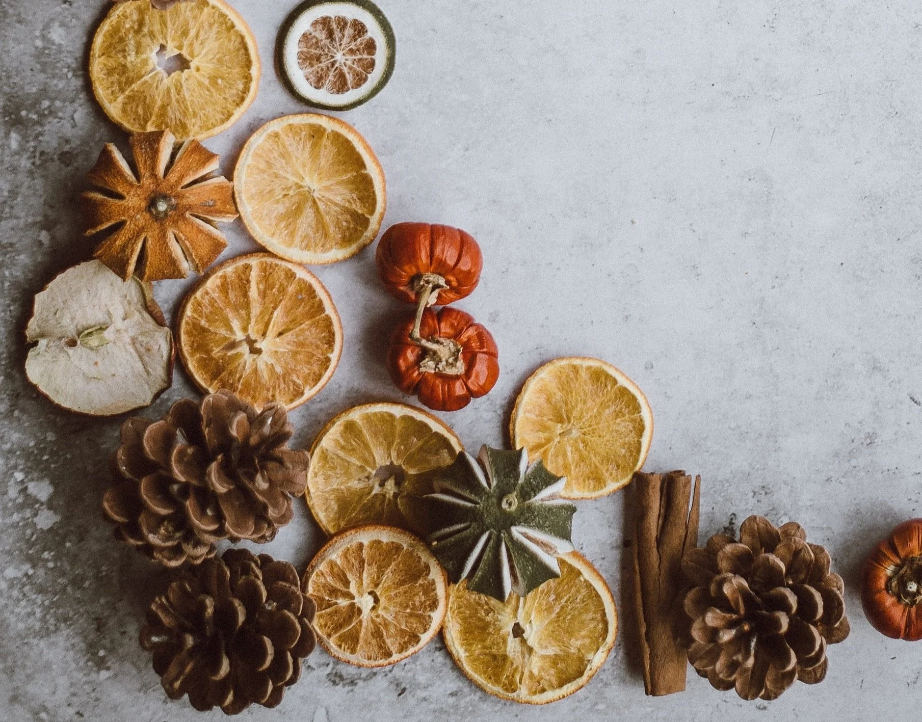 Dried oranges, cinnamon, apple and pine cones on a grey background