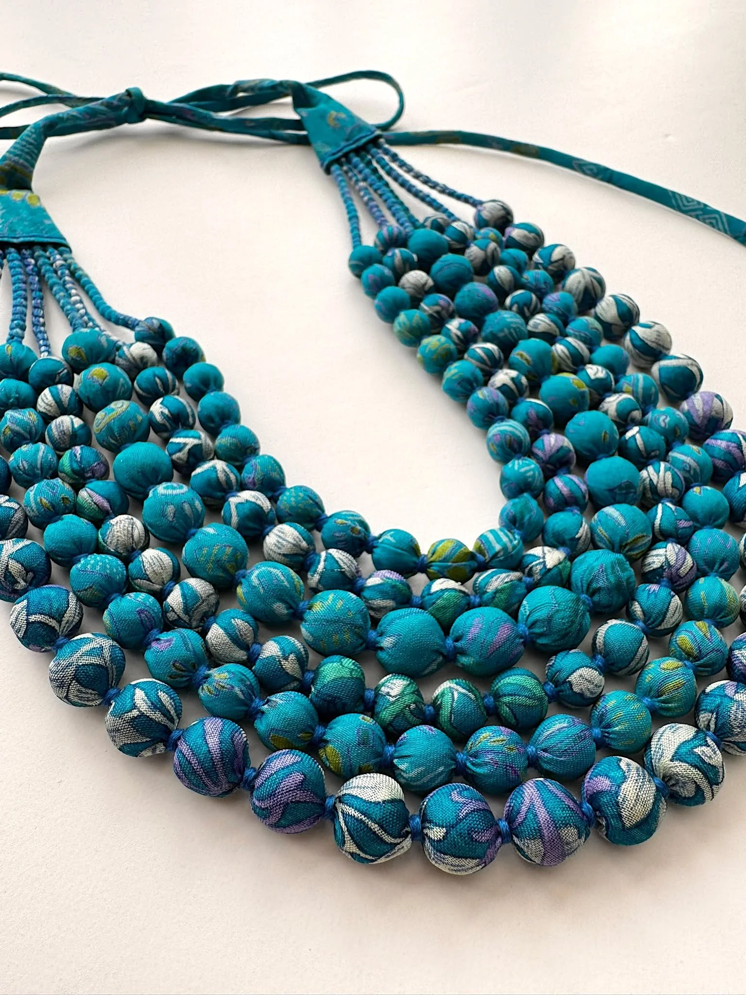 Upcycled blue sari silk necklace on a white background.jpeg