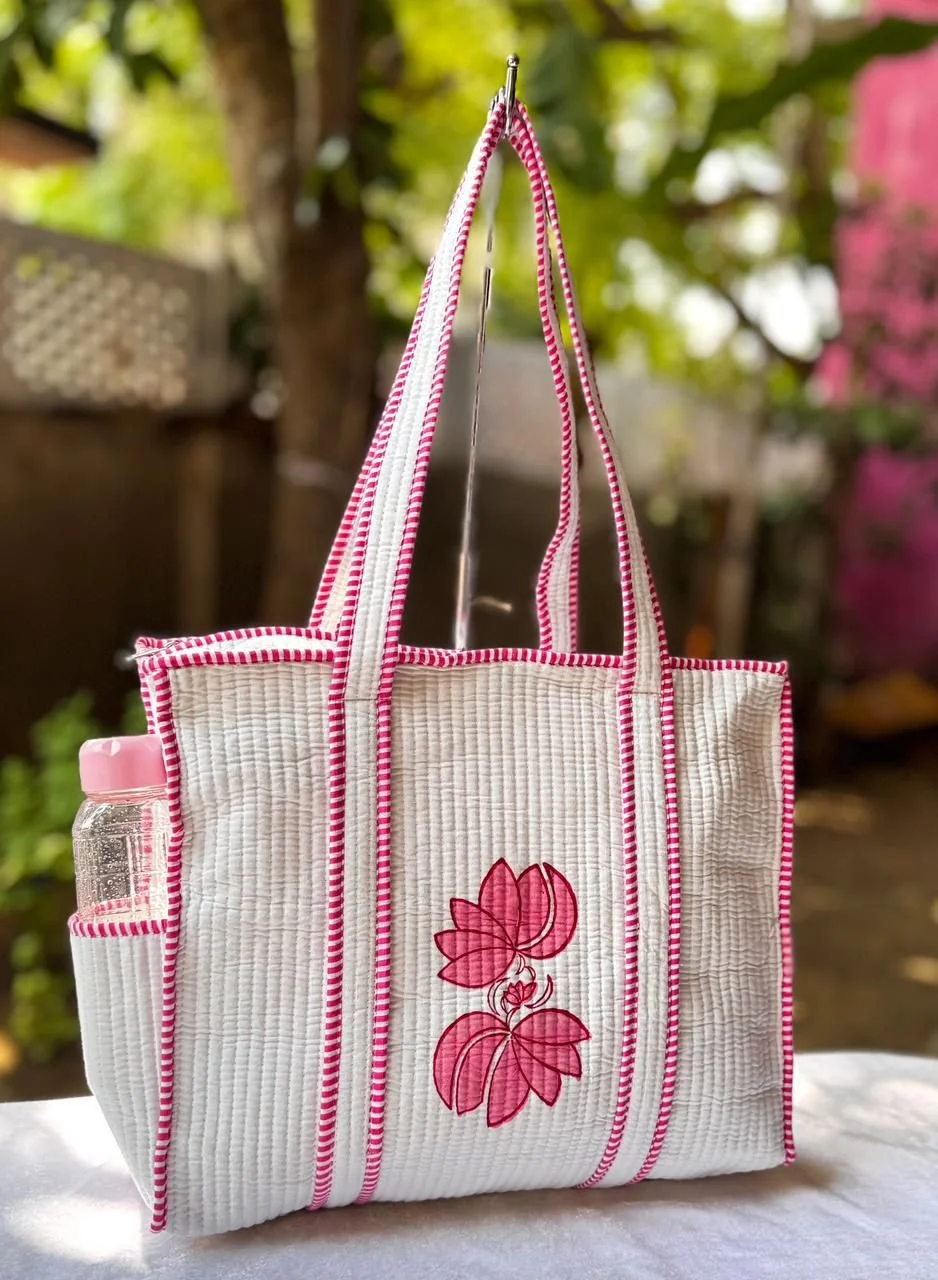 A floral print white and pink shopper bag with a flower design on the front resting on a table .