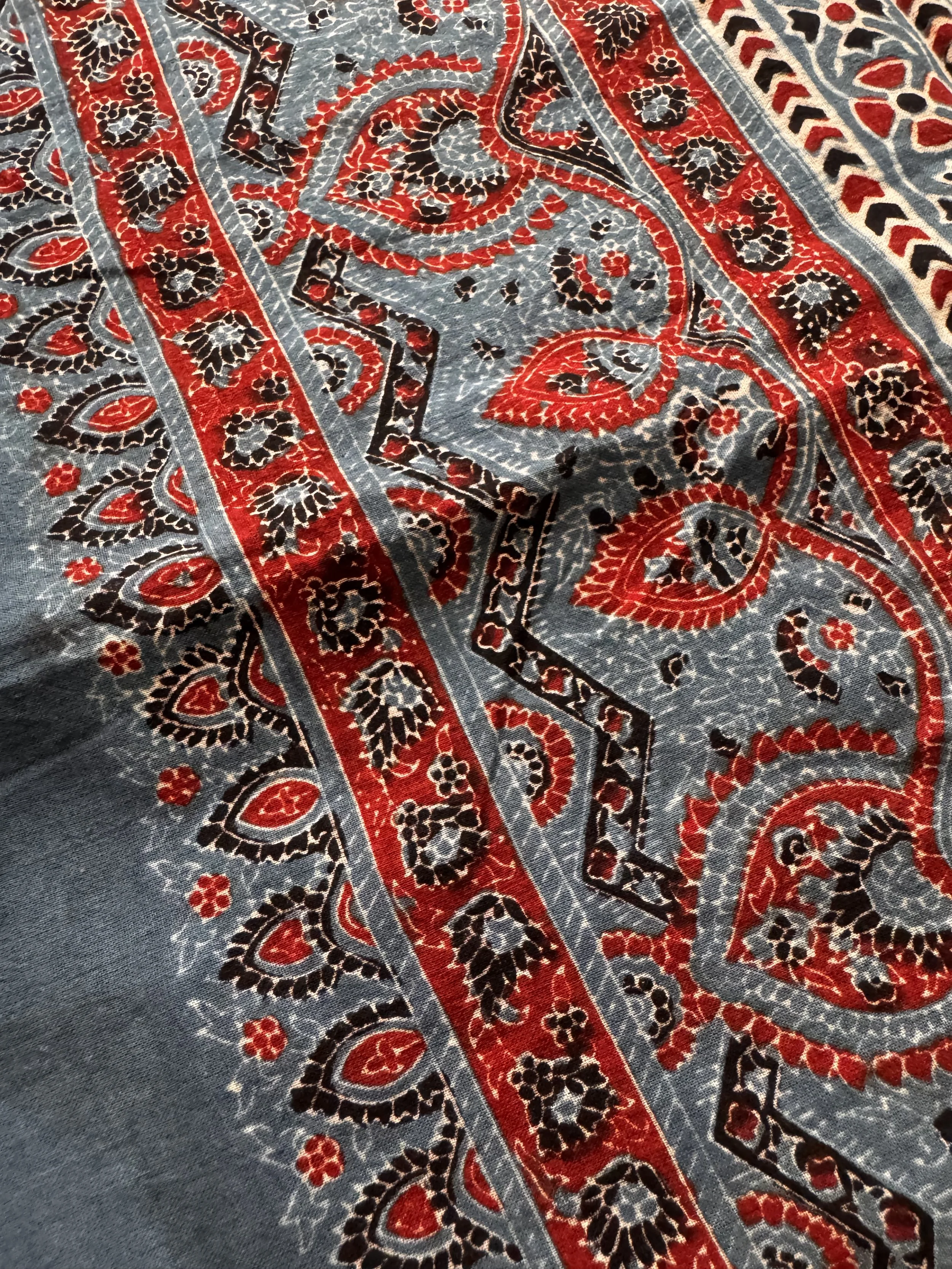 Close up of geometric and floral Ajrakh design in striking natural dyes of indigo, red madder and black iron on soft mulmul cotton
