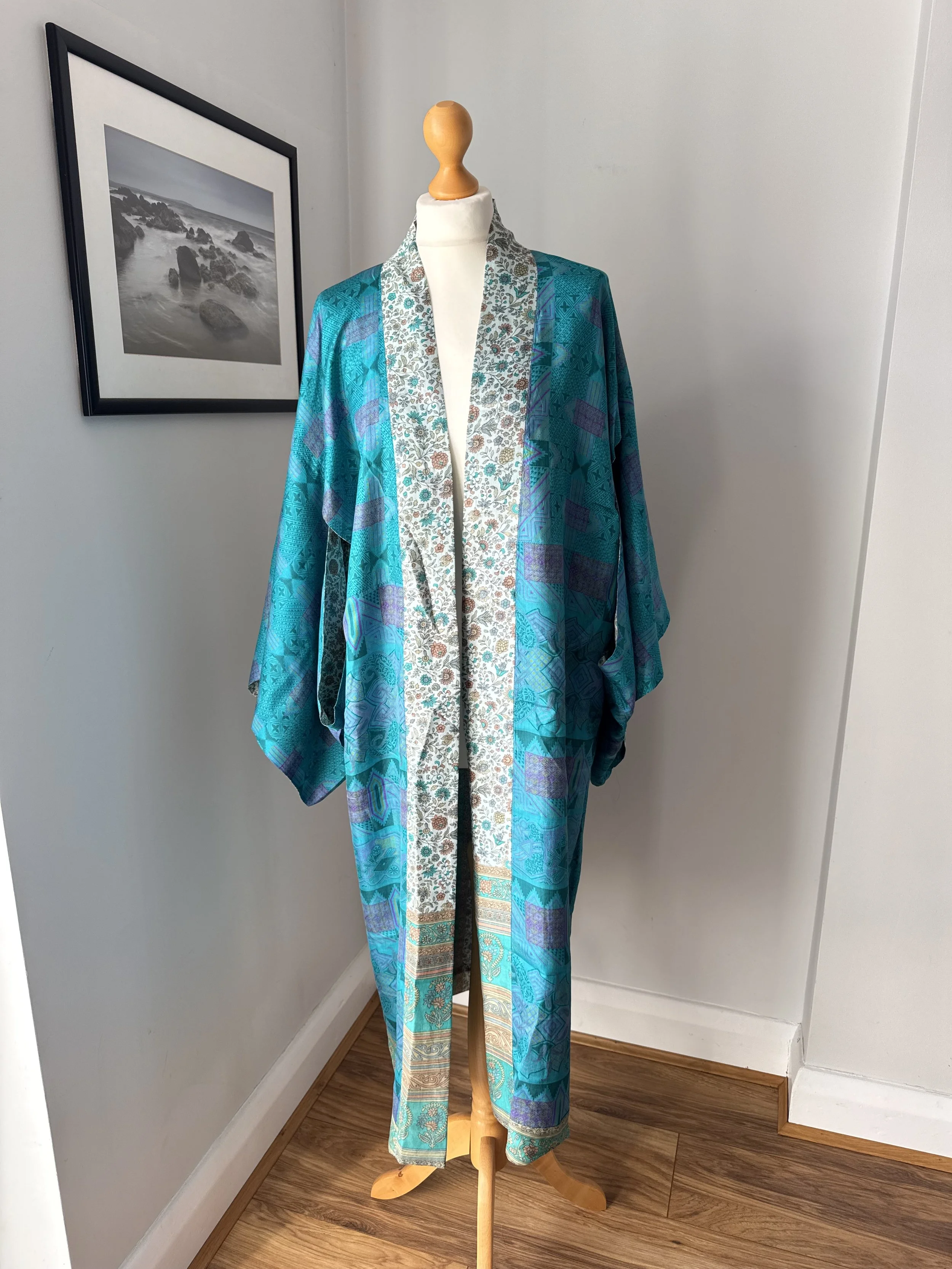 Inside lining of long sari silk kimono cover up with a floral border and striking turquoise abstract print lining on a white mannequin