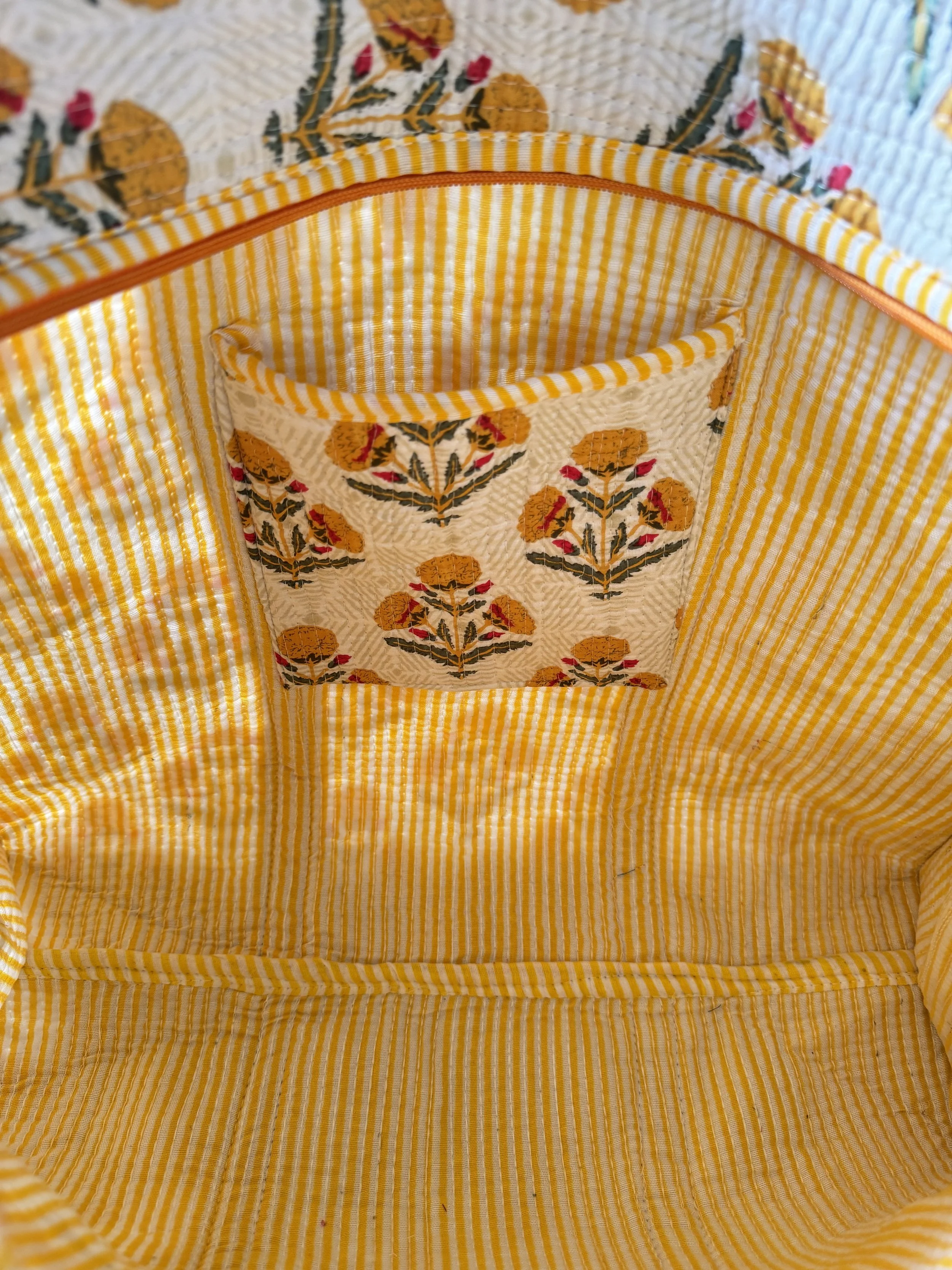 Inside striped lining and interior pocket of quilted cotton tote bag