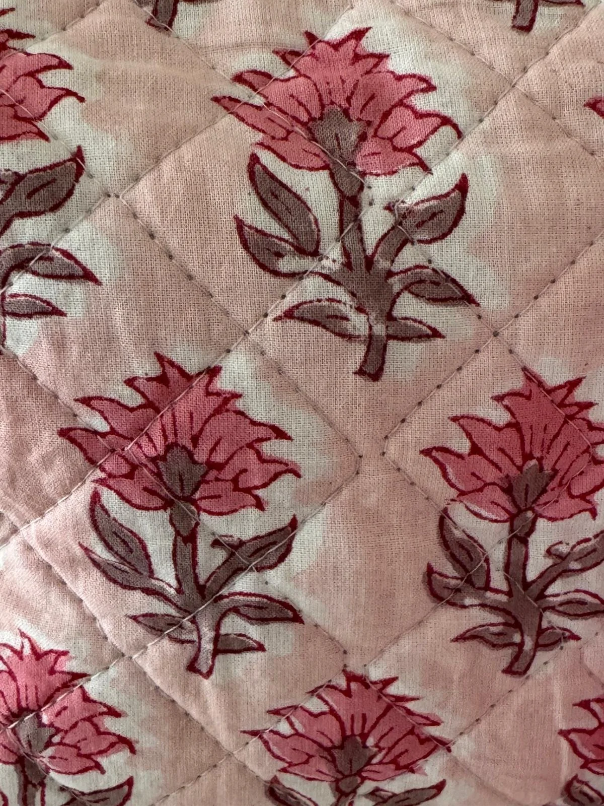 Close up of indian hand block printed floral design on a blush pink quilted wash bag