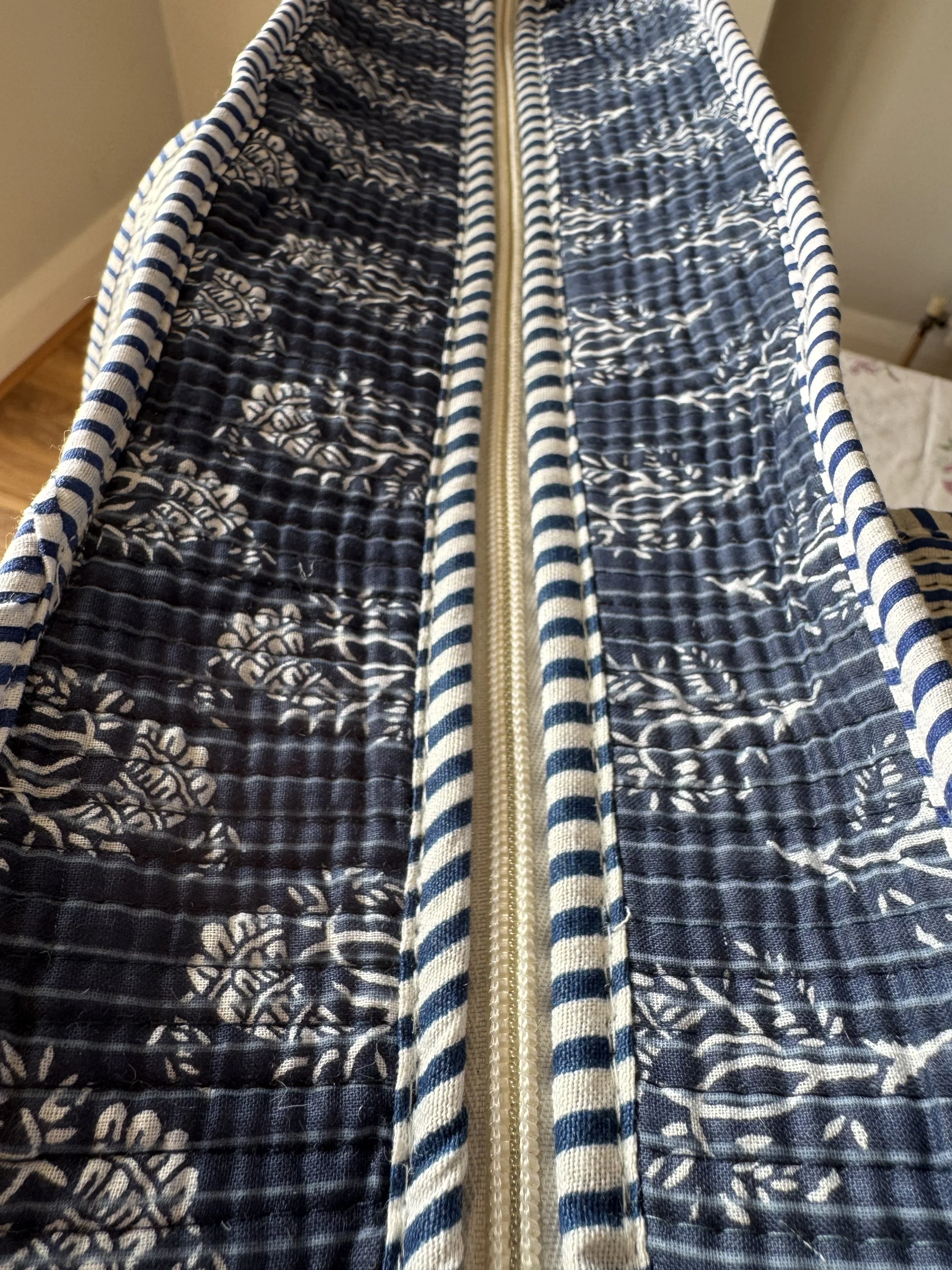 Secure zip fastening detail on navy blue screen printed quilted tote bag.