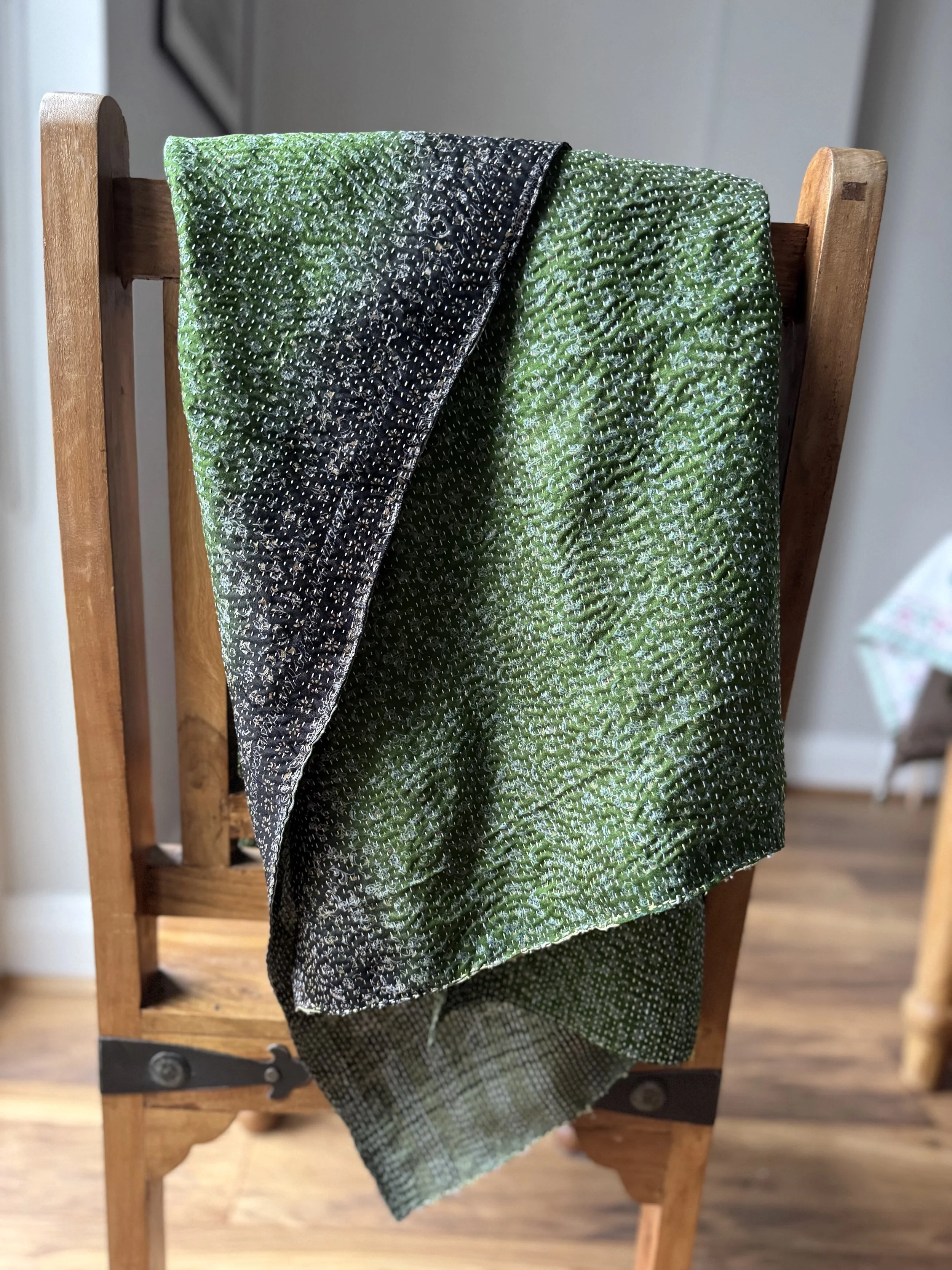 Reversible green recycled sari silk scarf in shades of emerald and olive draped over a wooden Jali style chair