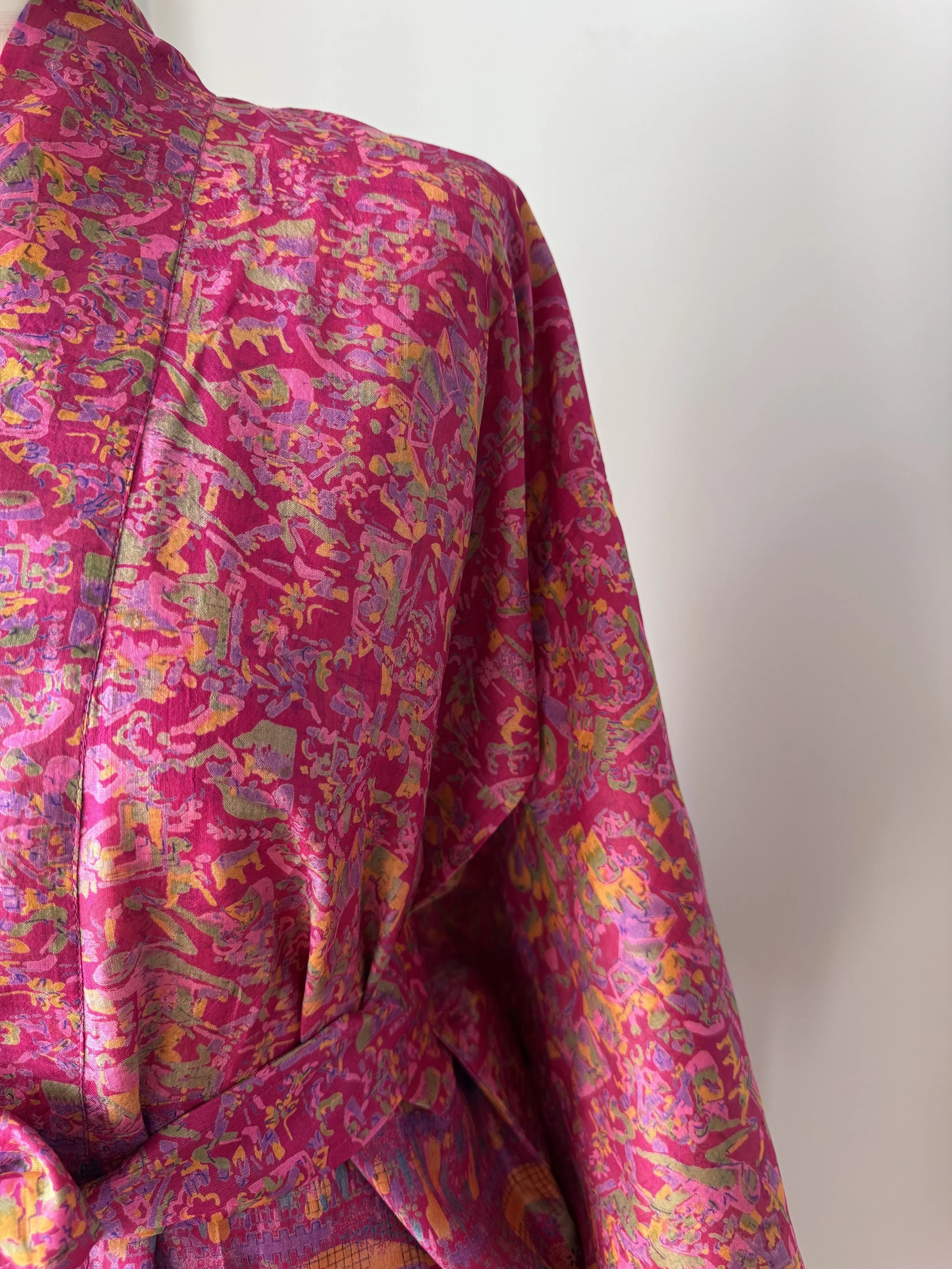 Detailed view of upcycled sari silk fabric in fuchsia pink with multi-coloured floral design