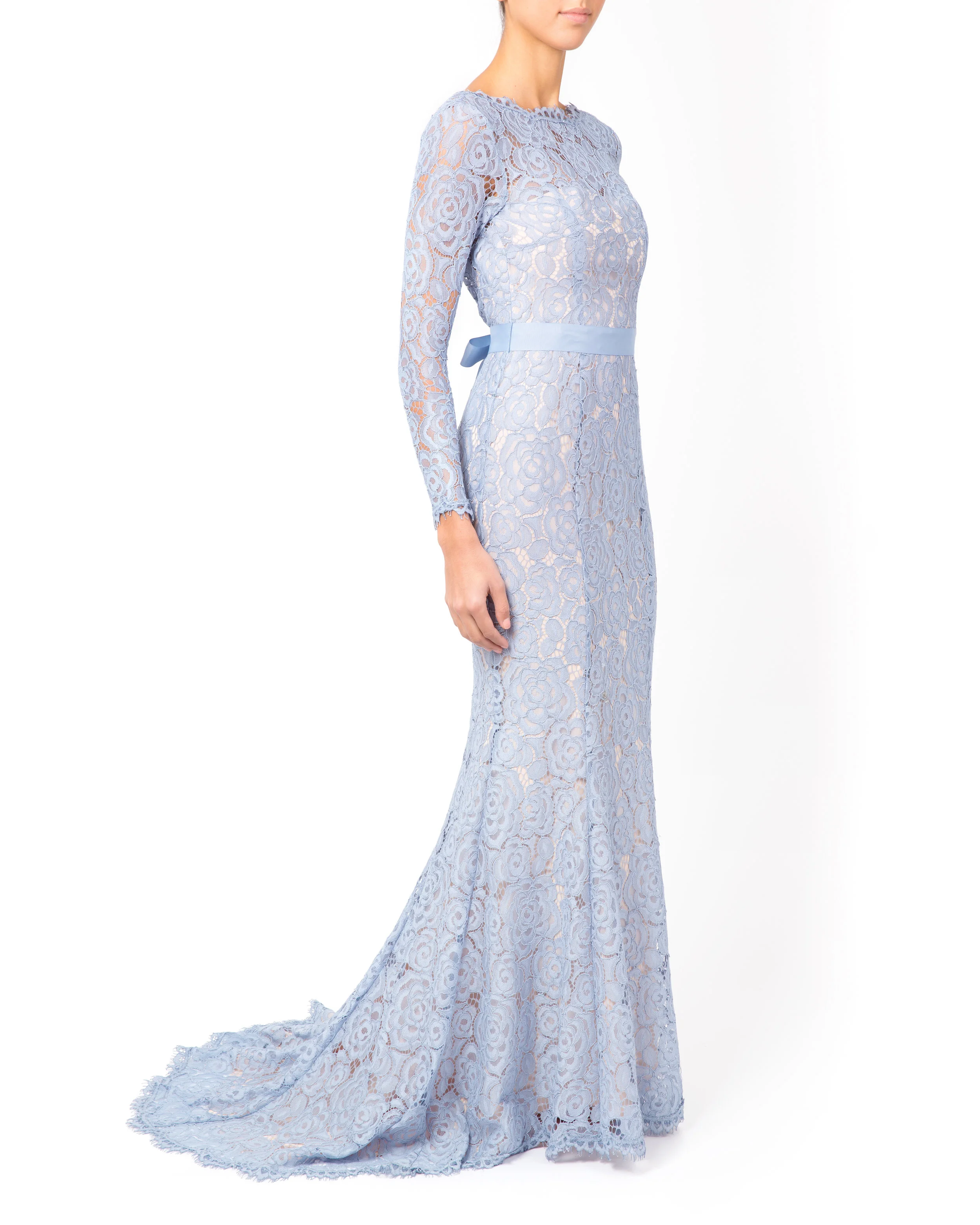 Model poses facing sideways wearing the light blue lace floor-length evening dress with sleeves.