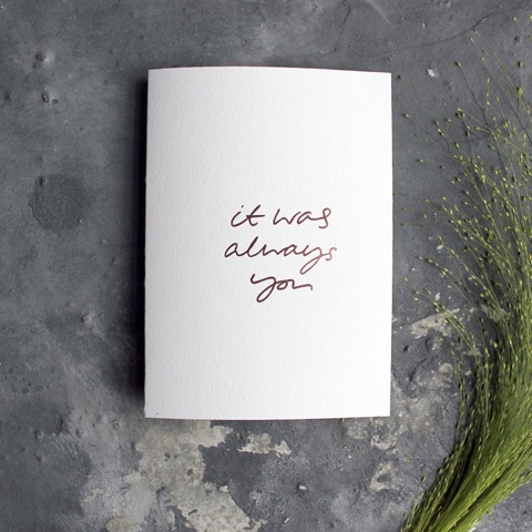 A white wedding card that reads, it was always you, in romantic calligraphy