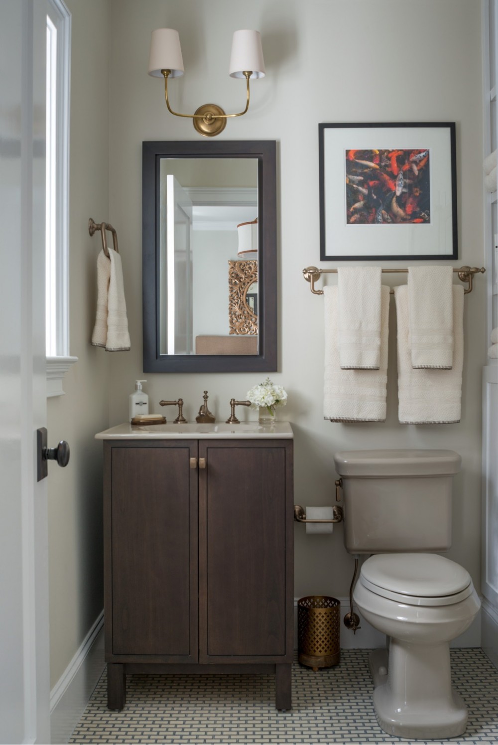   The second-floor guest bath’s palette echoes nature’s hues, with sand-colored fixtures, warm bronze faucets and a dark wood vanity.  