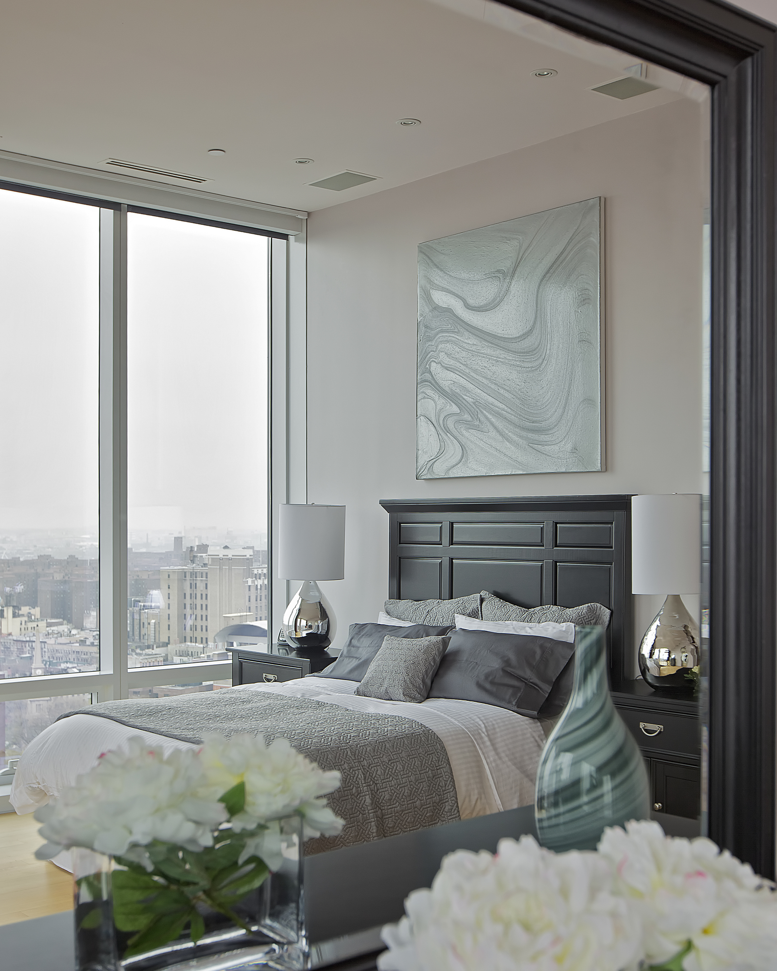   CHELSEA PENTHOUSE DUPLEX   A classic color scheme brings an elegant and luxurious feel to the bedroom. A gray and white space infused with dark brown wooden work decorates the space. The vase and lamps add a modern touch to the room. Wake up to the